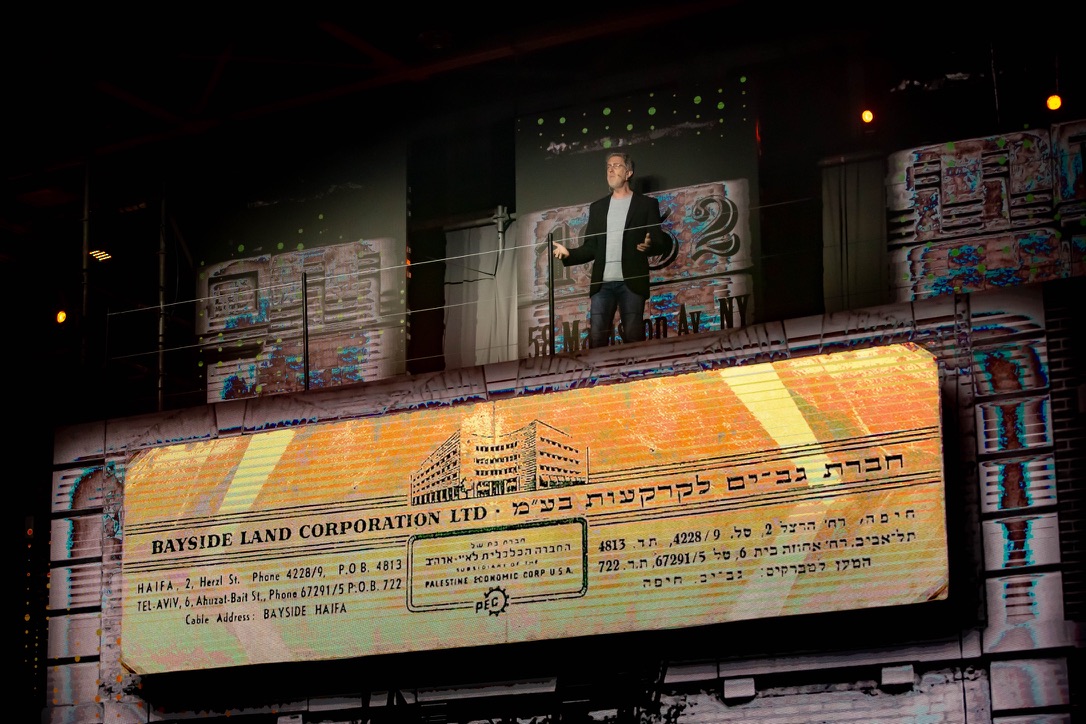 Speaker presenting Gav-Yam’s historical legacy with vintage Bayside Land Corporation visuals at 90th anniversary event.