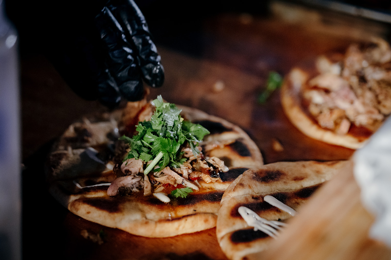Live food station preparing fresh Middle Eastern wedding snacks like topped flatbread or laffa with meat and cilantro at a wedding in Israel.