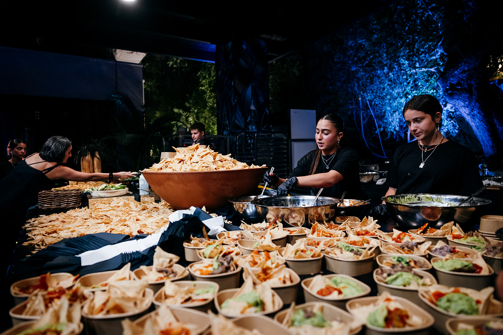 Unique late-night snack catering at an Israel destination wedding with large bowls of nachos, tacos, and fresh toppings being prepared by staff.