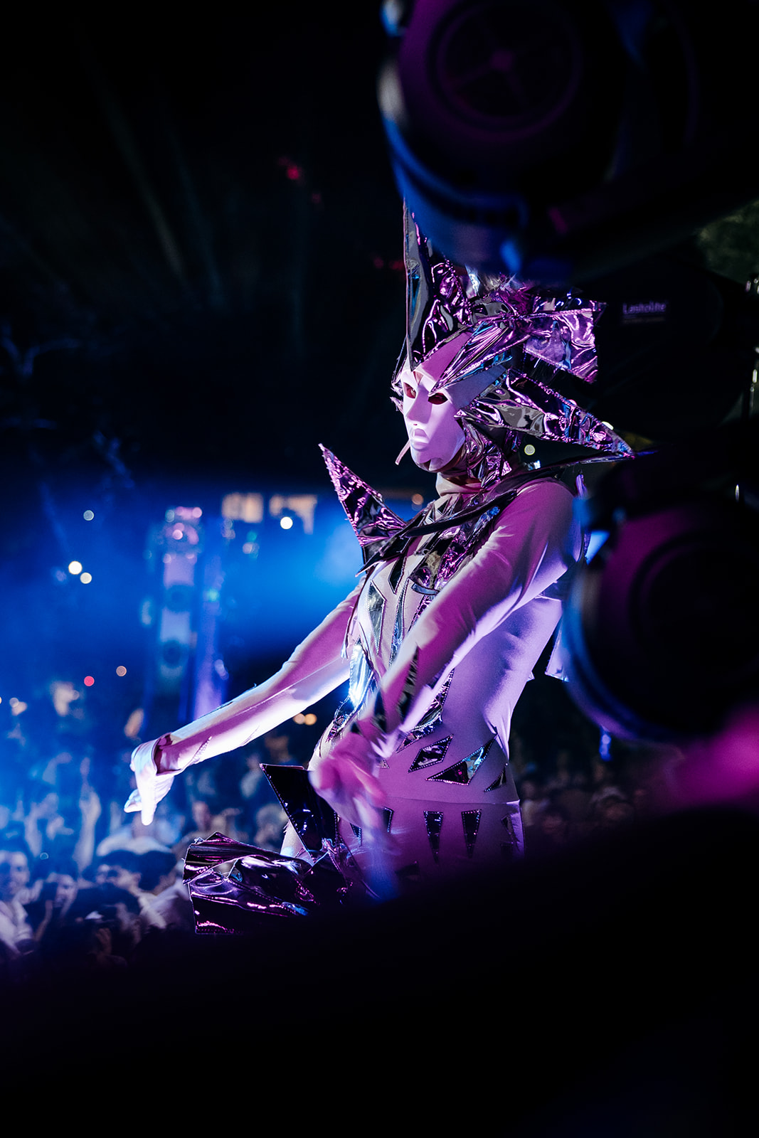 Futuristic performer in a chrome mask and costume hyping up the crowd at a high-energy Israeli wedding party reception.
