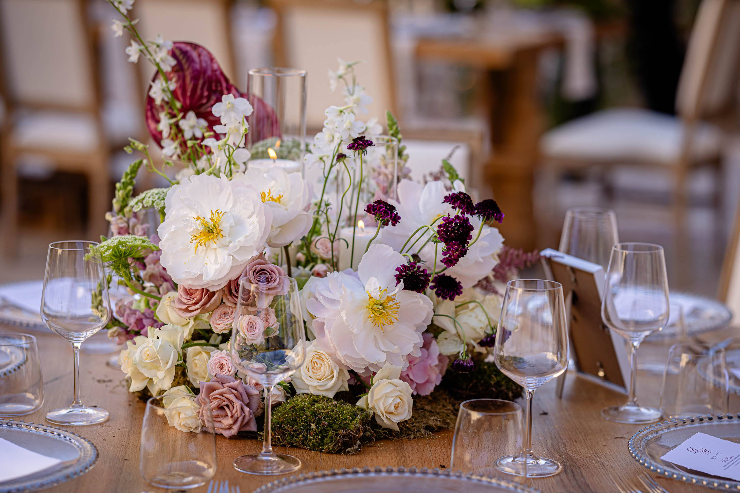 Elegant wedding table centerpiece with white peonies, roses, deep burgundy flowers and candlelight at the Tower of David in Jerusalem.