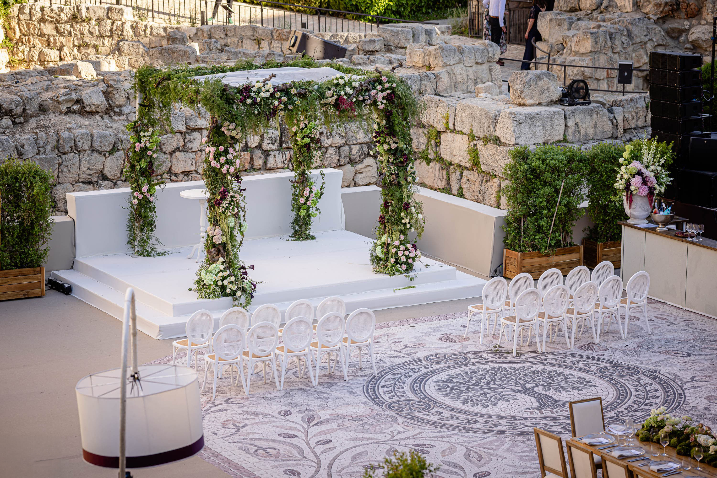Elegant floral chuppah and wedding ceremony setup surrounded by historic stone walls at the Tower of David in Jerusalem.