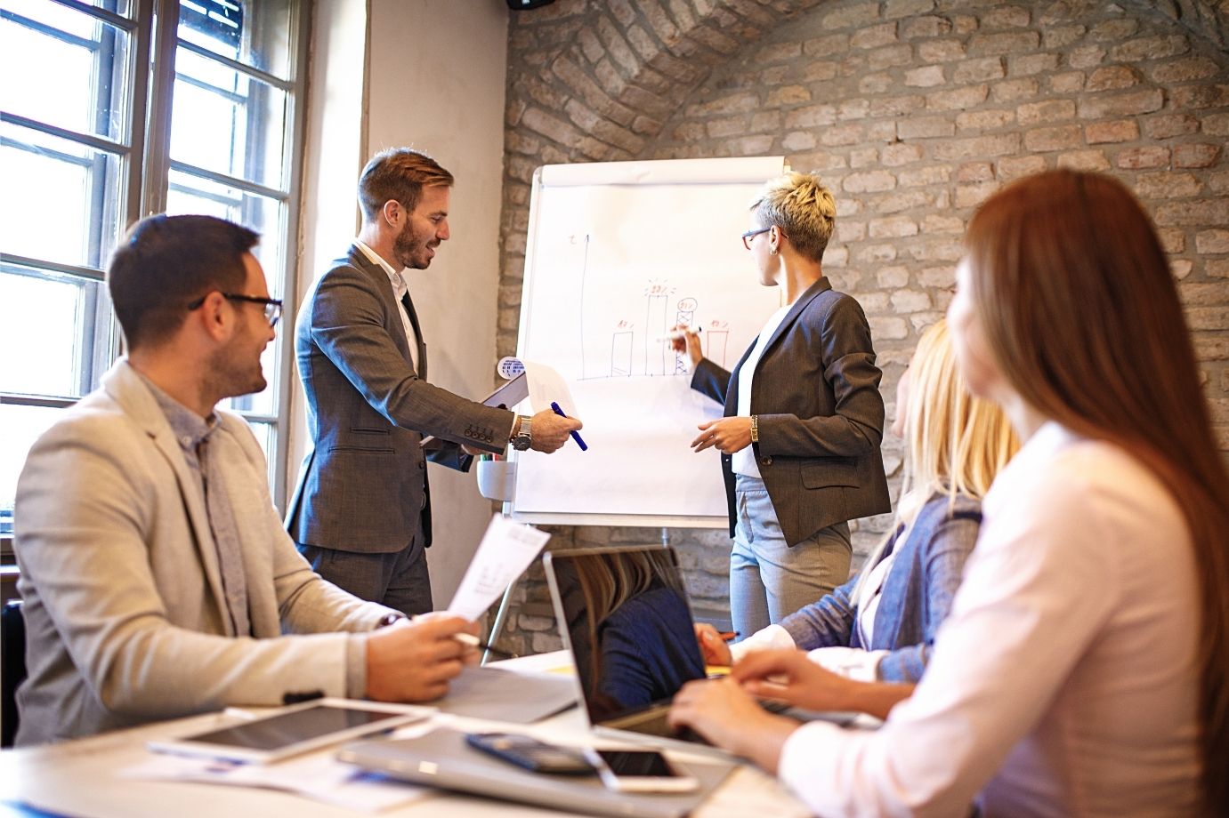 Group of professionals in a meeting with one person presenting on a whiteboard, symbolizing Schology’s commitment to transparency in sharing only verified scholarships