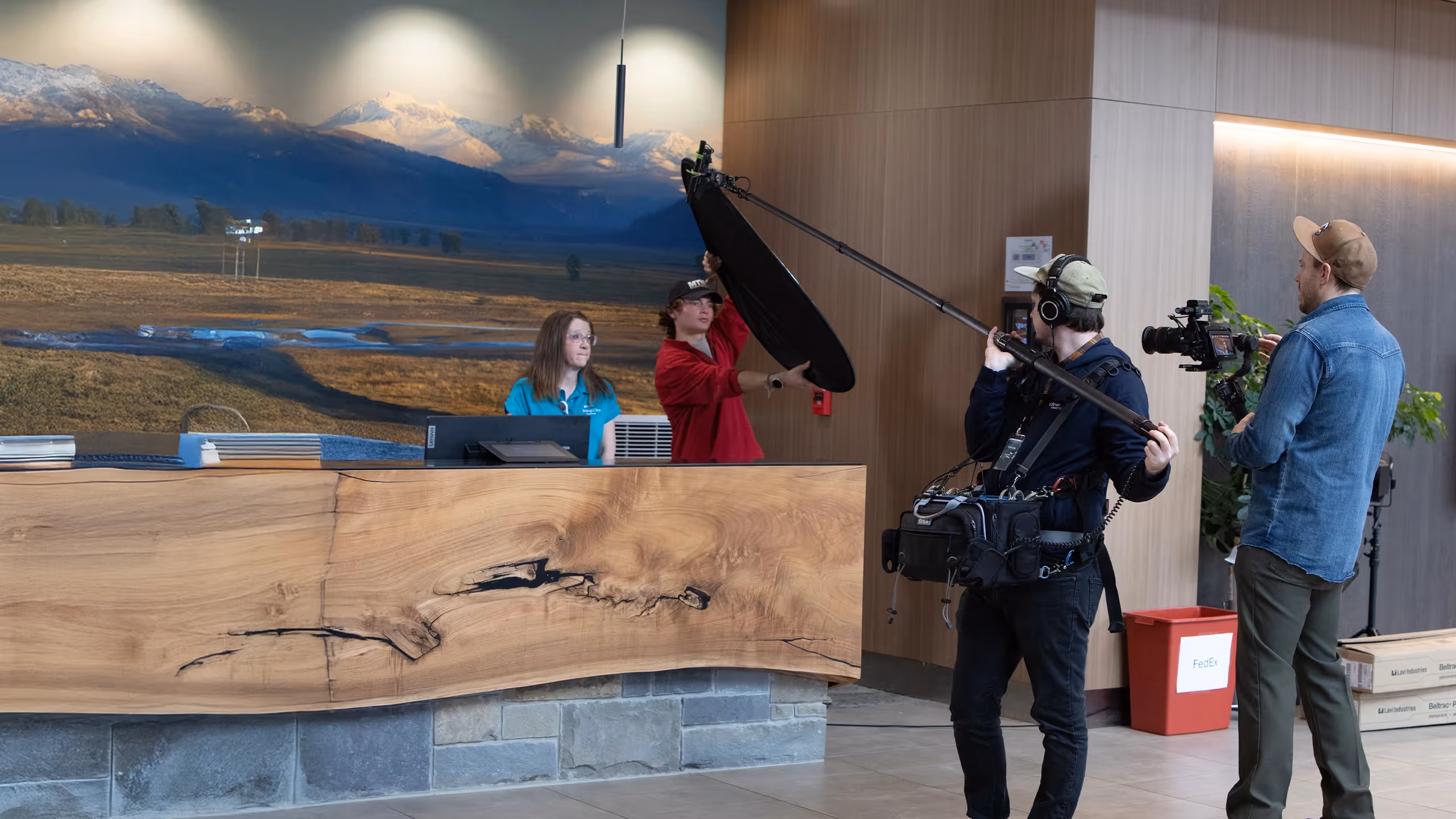Videography crew filming inside a lobby while two people stand at a reception desk.