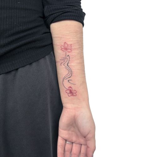 Underarm tattoo with a thin black abstract line and two red floral designs above and below it.