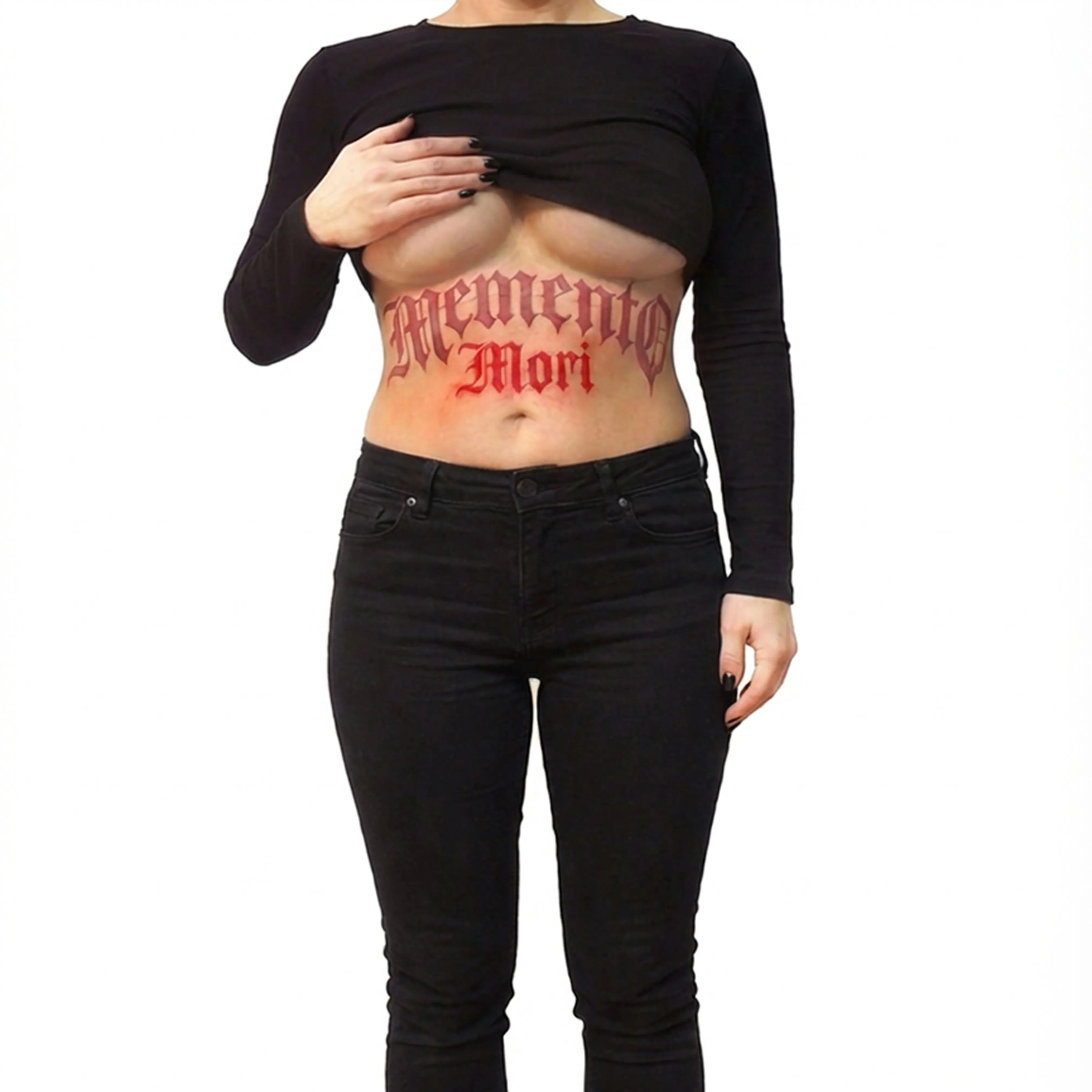 Person med sort tøj løfter trøjen og viser en stor tatovering på maven med teksten 'Memento Mori' i rød script.