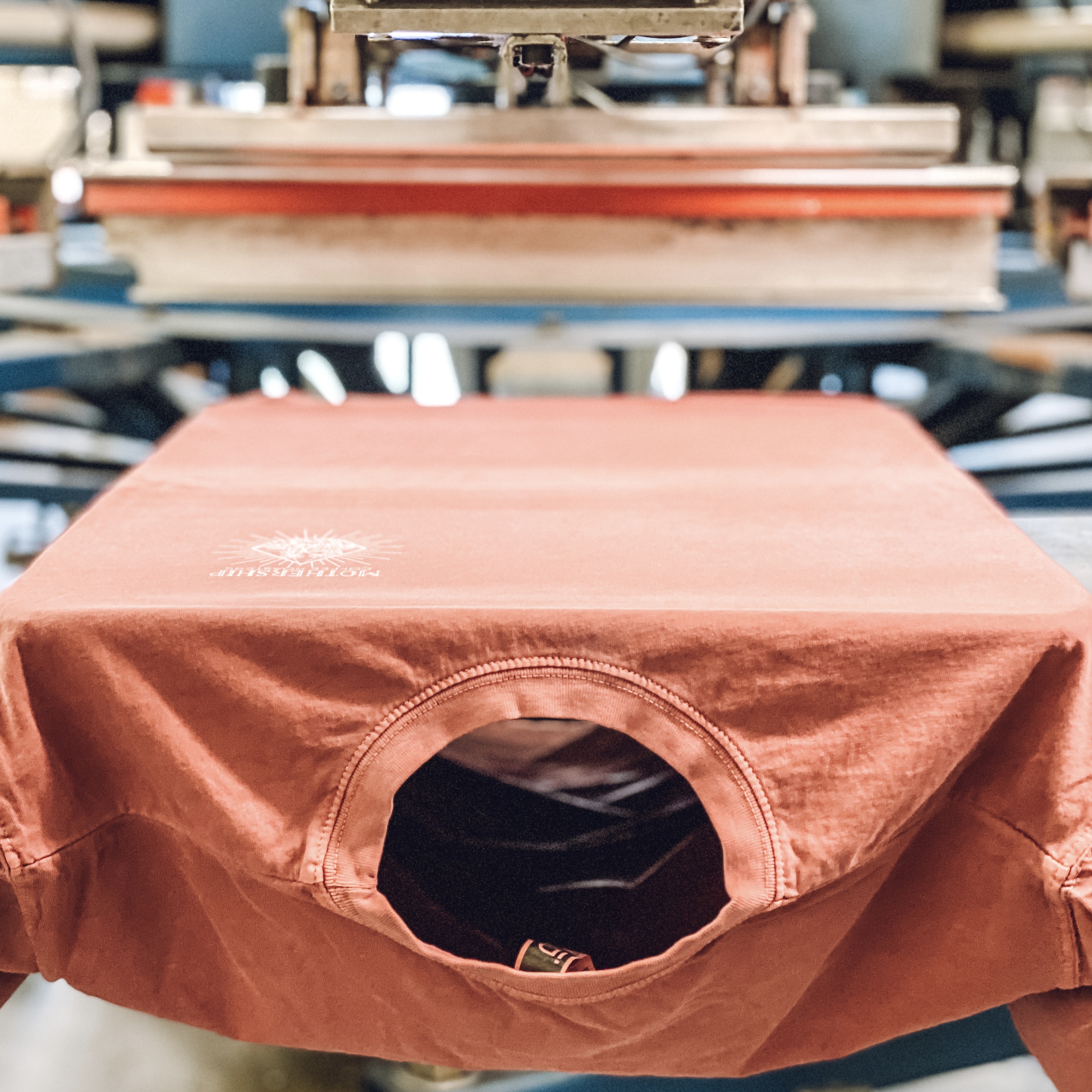 Red t-shirt being screen printed on an automatic press