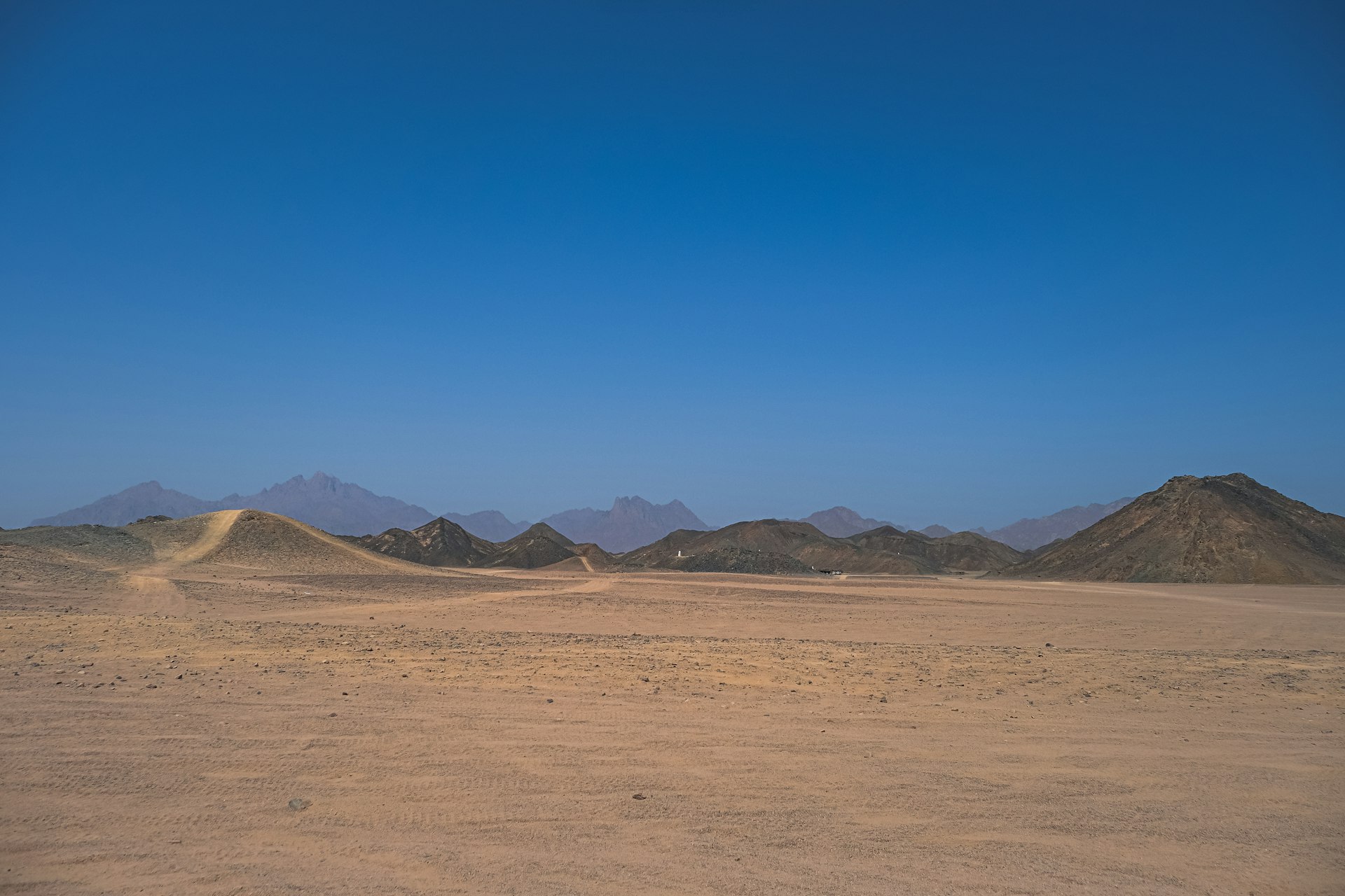 Weite Wüstenlandschaft mit sanften Hügeln auf der Strecke Marsa Alam – Luxor