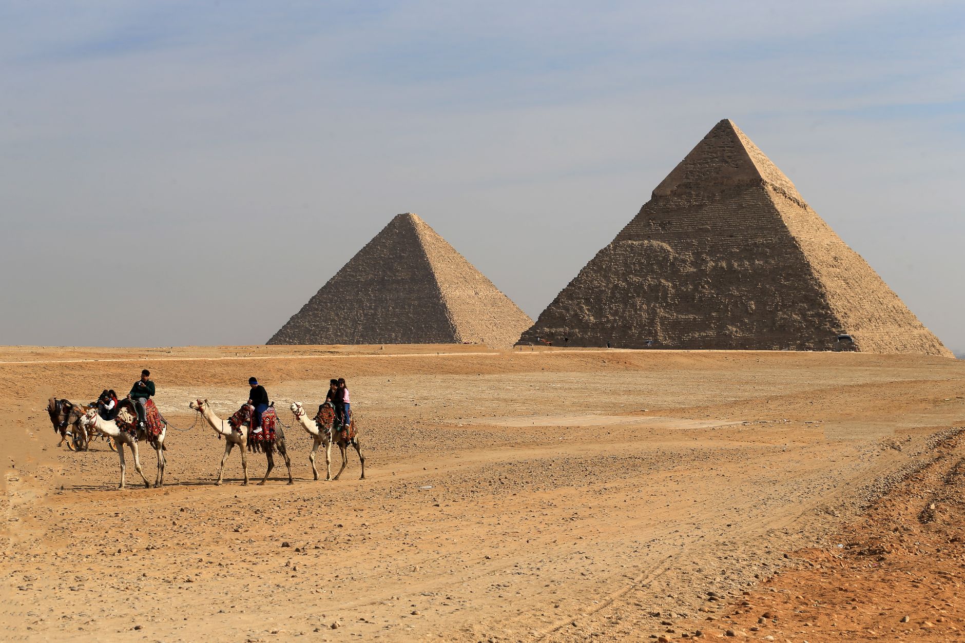 Familie auf einem Kamel vor den Pyramiden mit lachenden Kindern