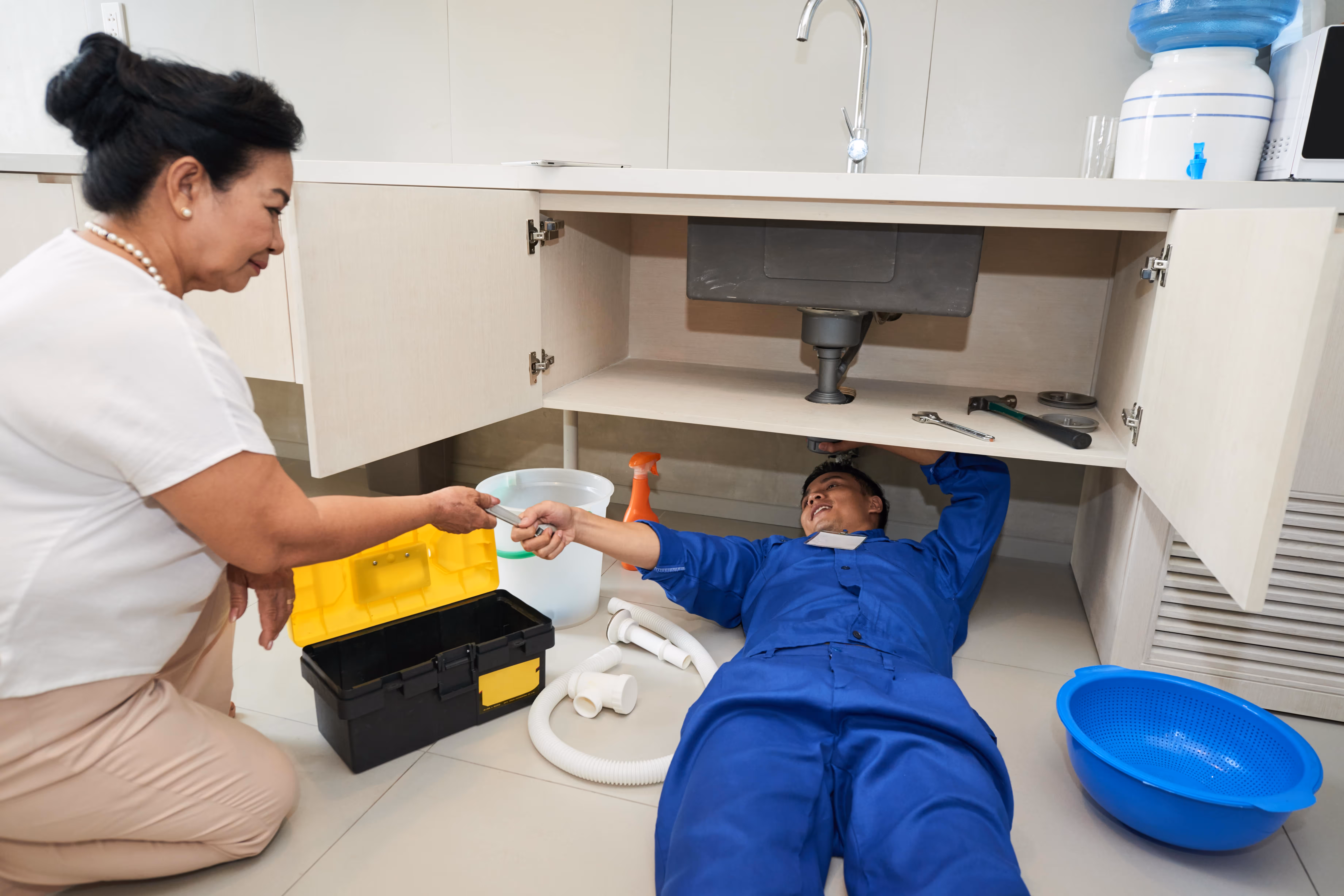 Plumber fixing a pipe under a kitchen sink. 
