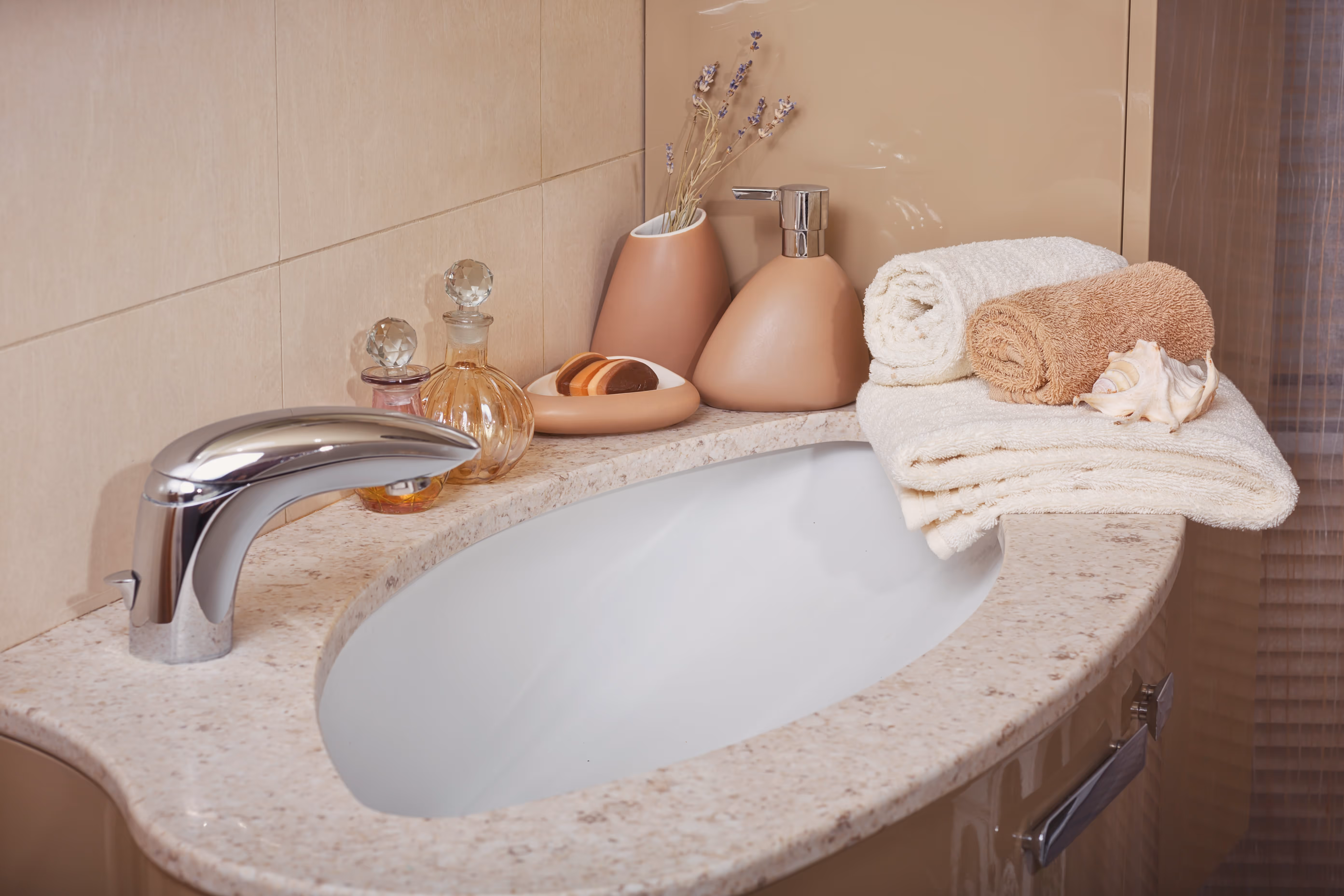 Stack of towels and a soap dispenser sitting on a counter next to a bathroom sink.