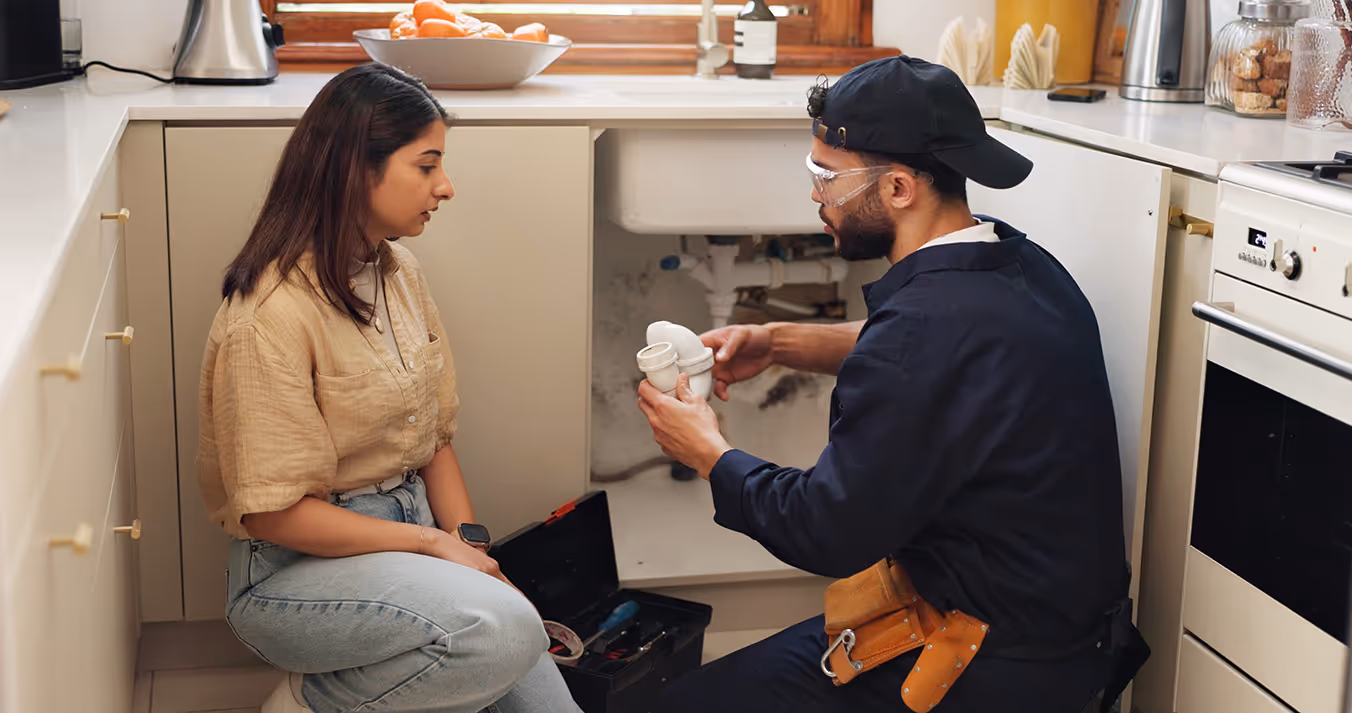 A plumber having a discussion with a client in front of a sink.
