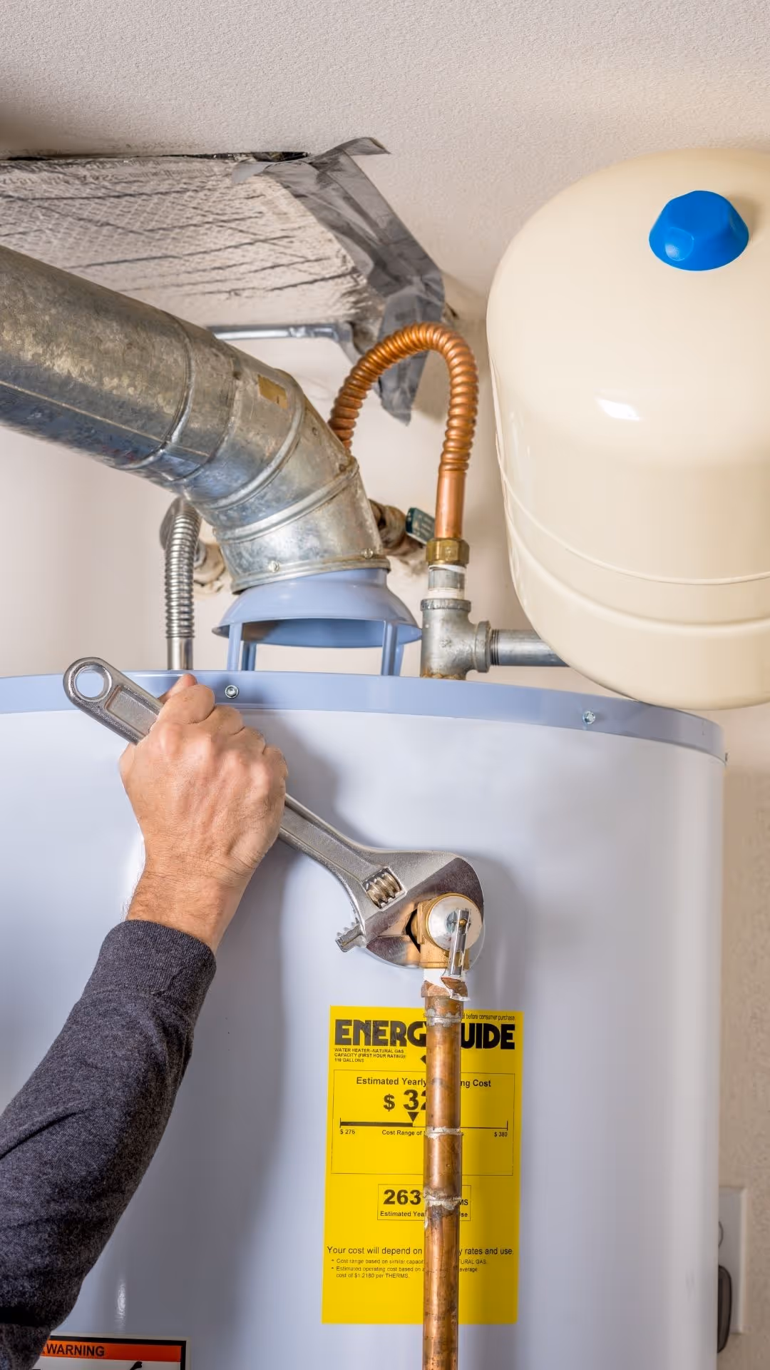Hand with wrench in it adjusting a water heater.