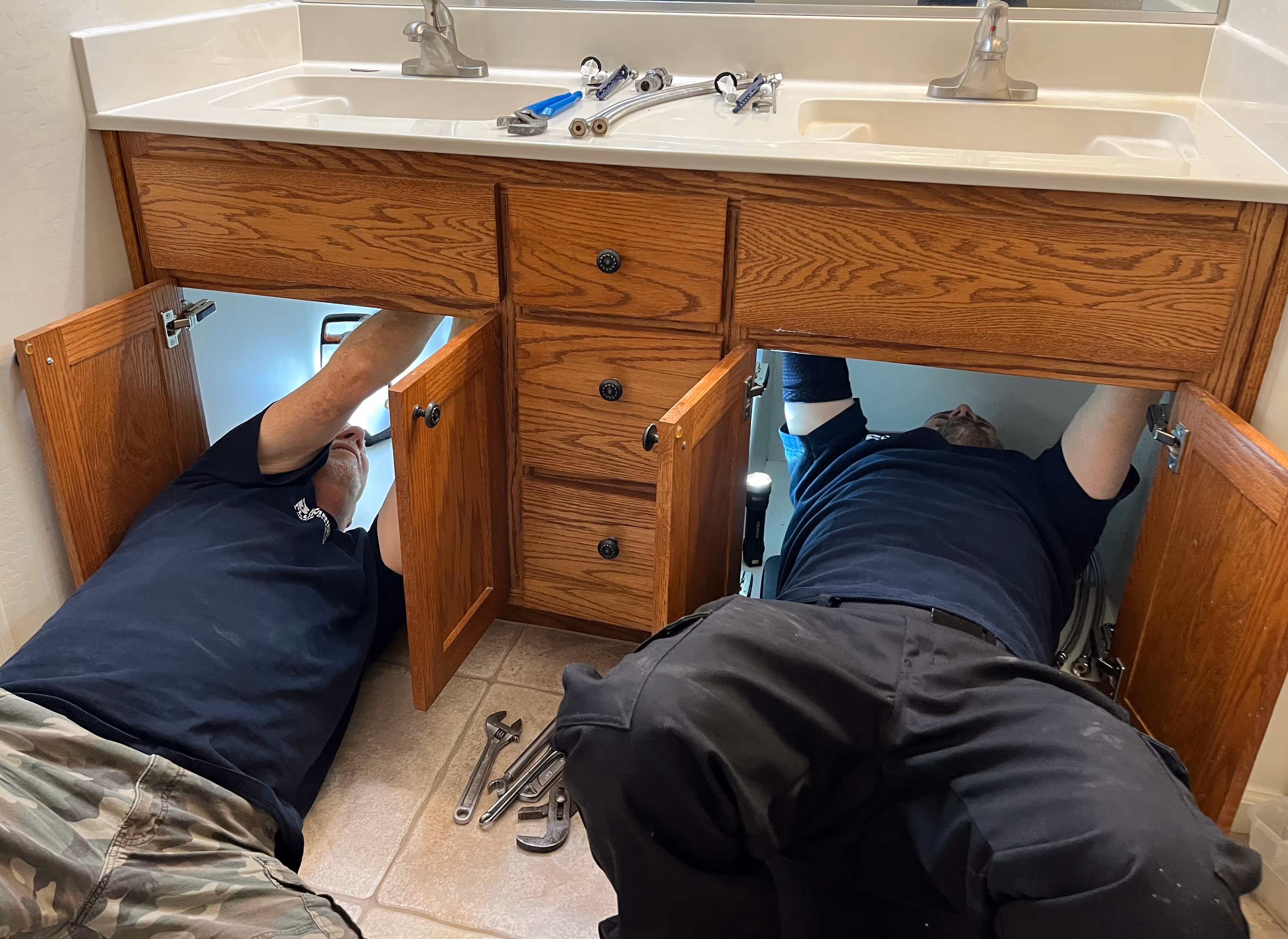 Twp plumbers working under the bathroom sink