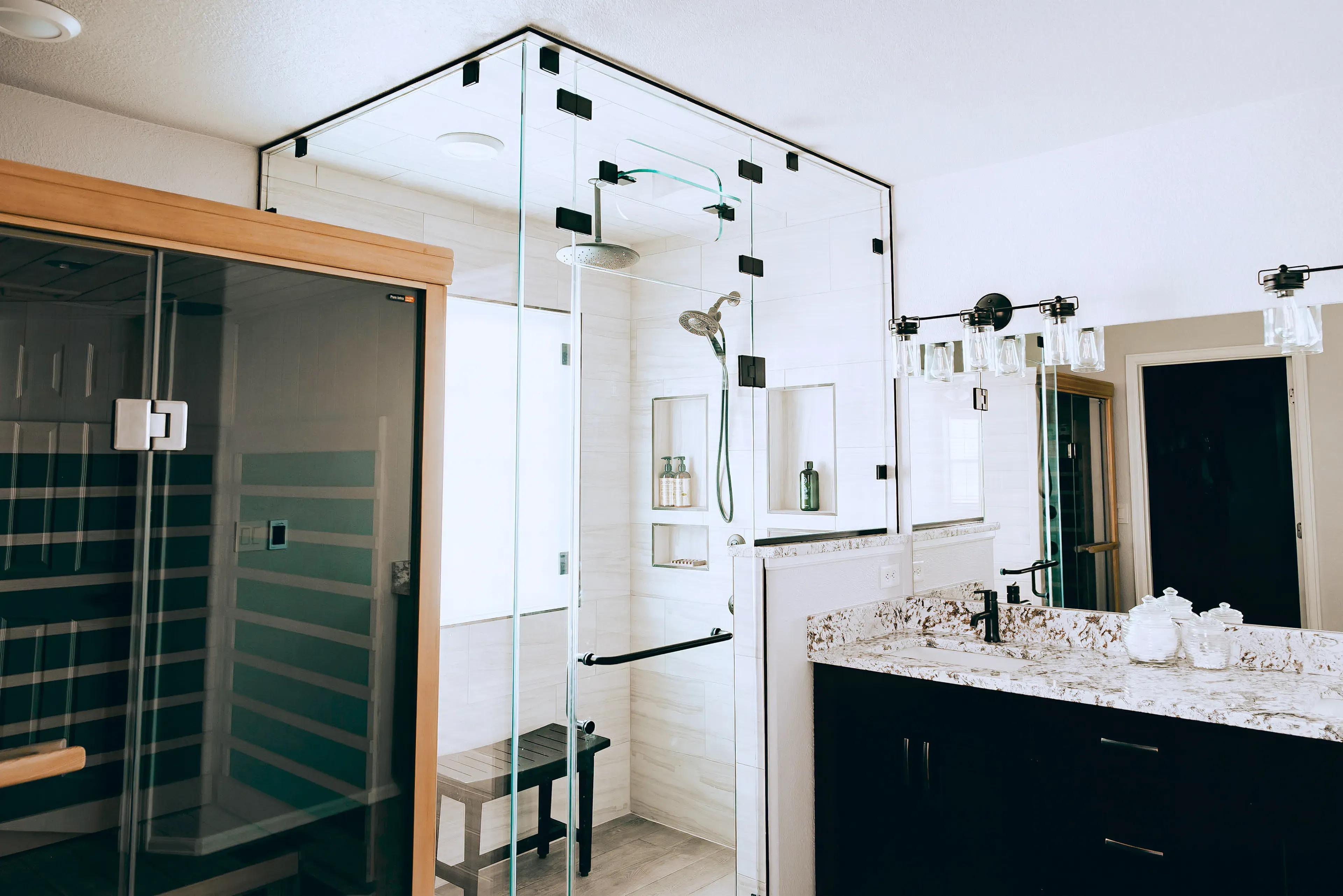 Modern bathroom featuring a glass-enclosed walk-in rainfall shower, wooden sauna, and granite countertop vanity.