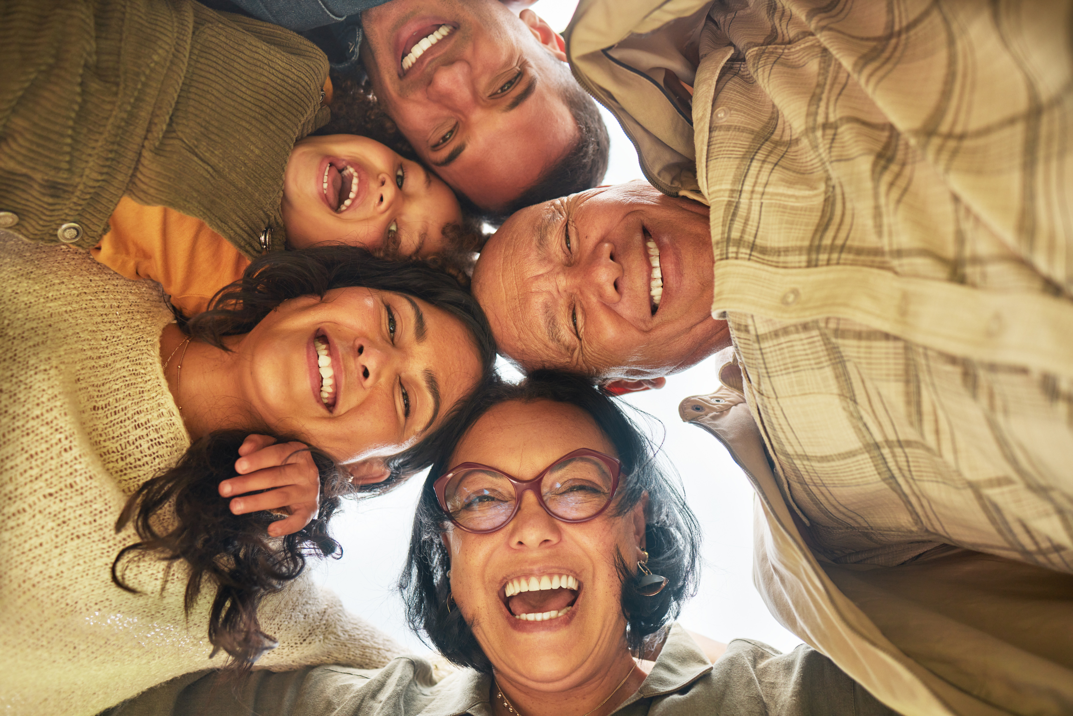 A family huddled together in a circle looking down at the camera.