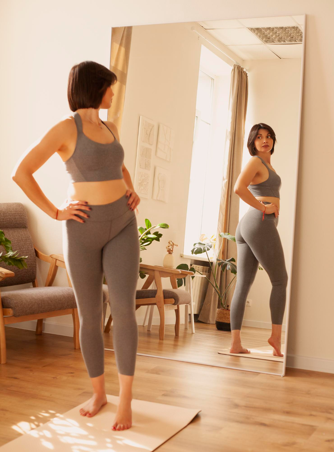 A woman in workout clothing checking herself out in the mirror.