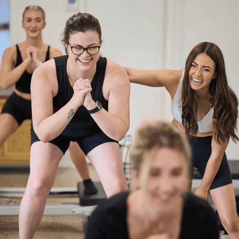 Instructor laughing with clients during a reformer class