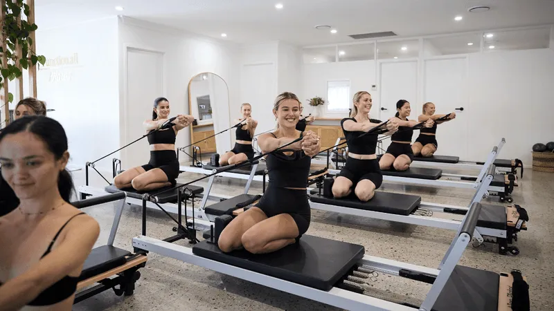 Group reformer class with clients kneeling on the reformers