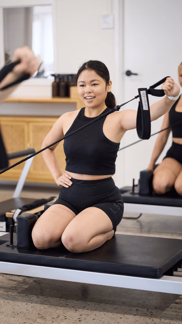 Client doing kneeling strap work on a reformer