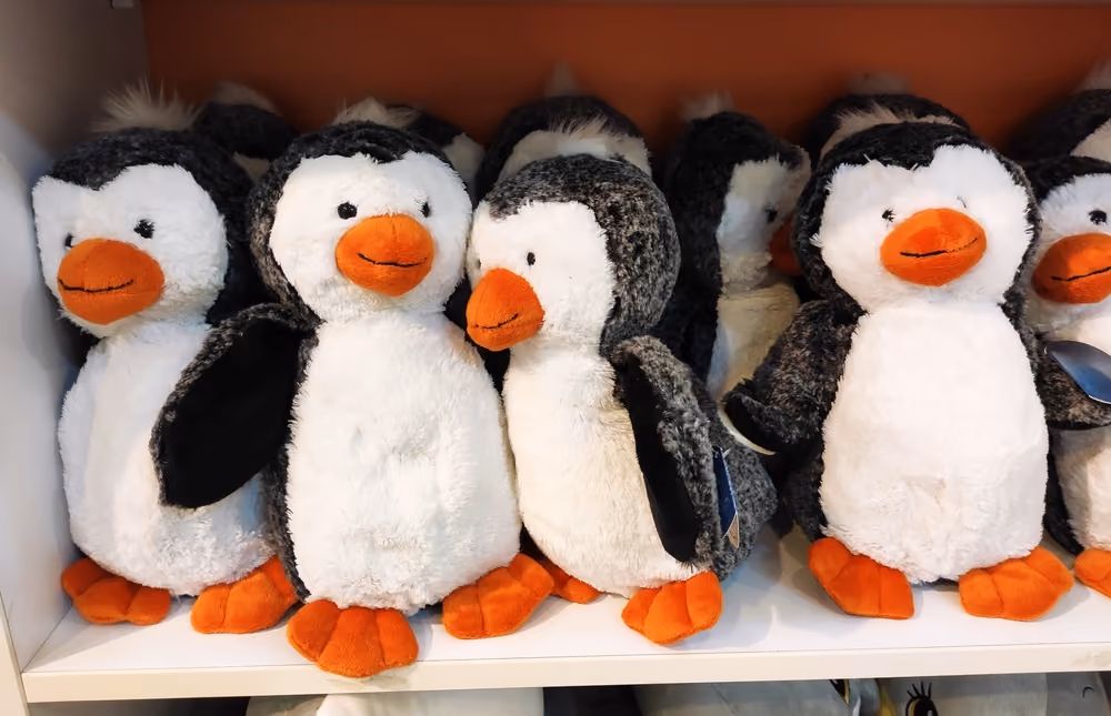 Shelves filled with plush penguin toys with orange beaks and feet.