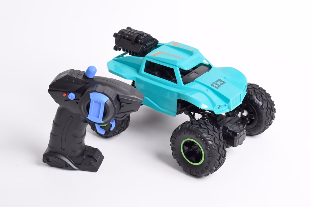 Black and blue remote control next to a turquoise RC off-road truck with large tires.