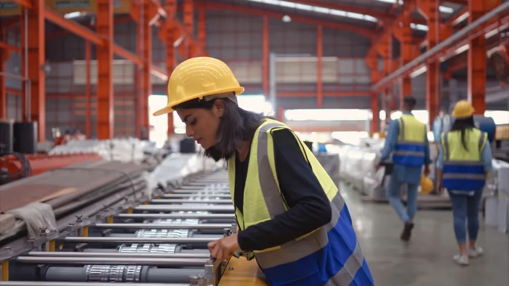 Worker inspecting a large metal component on a production line.