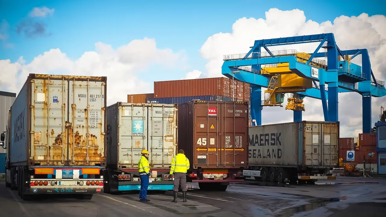 Two workers walking through a shipping container yard.