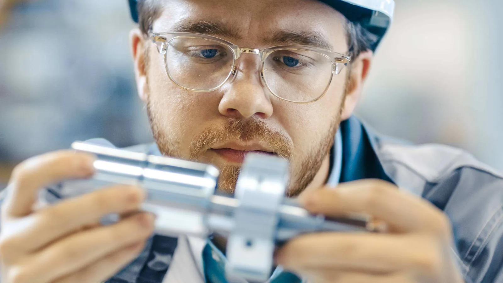 Worker measuring metal component.