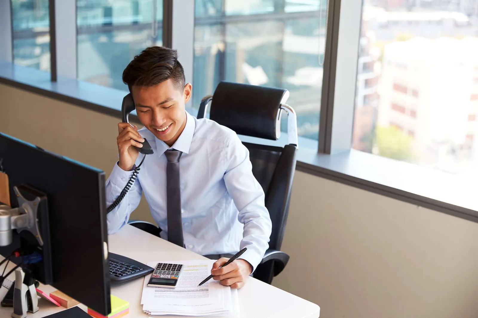 Office worker using phone and laptop.