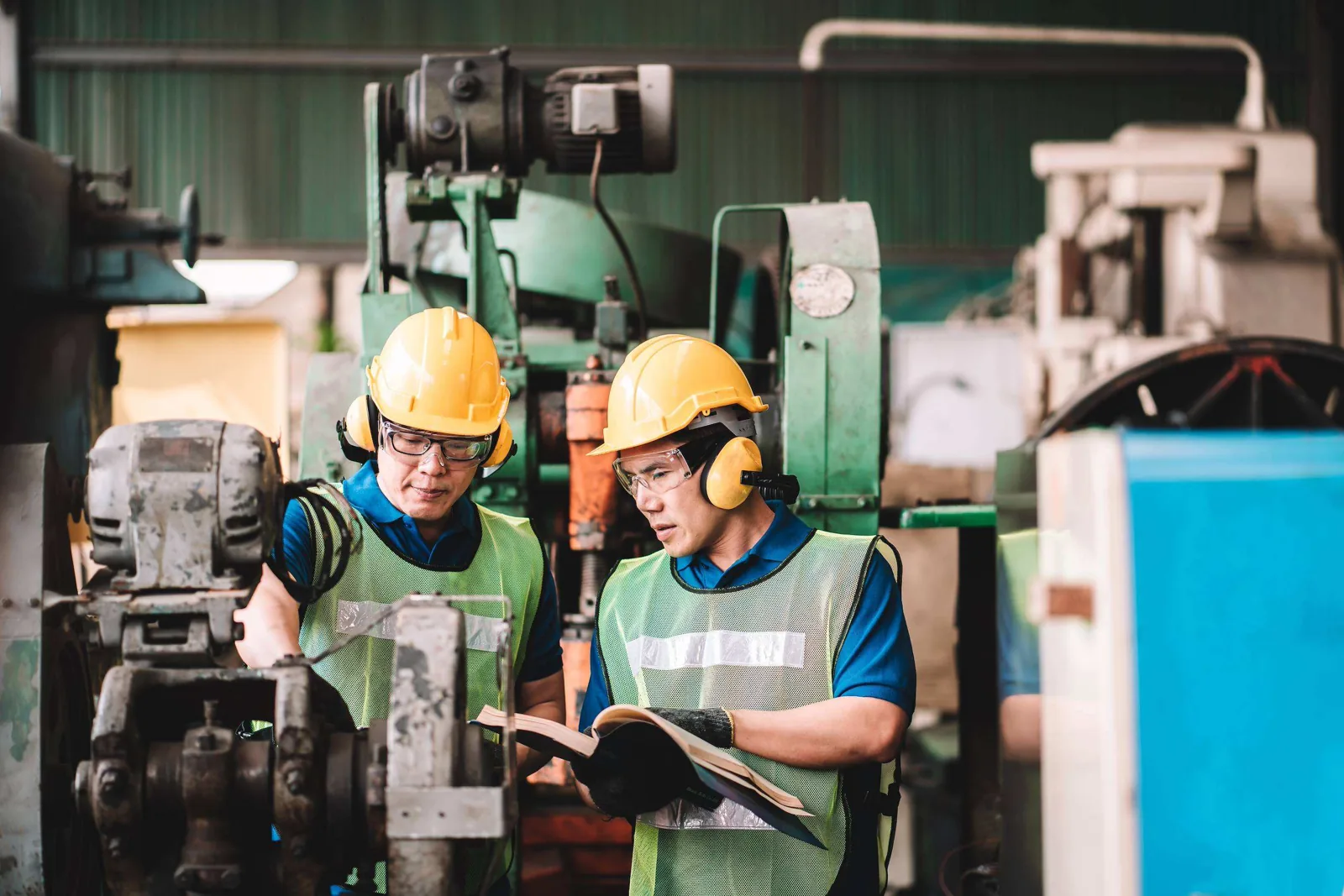 Two workers discussing machine.