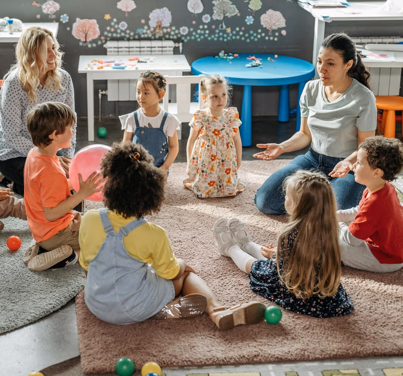 A group of children sitting on a rug in a classroom.