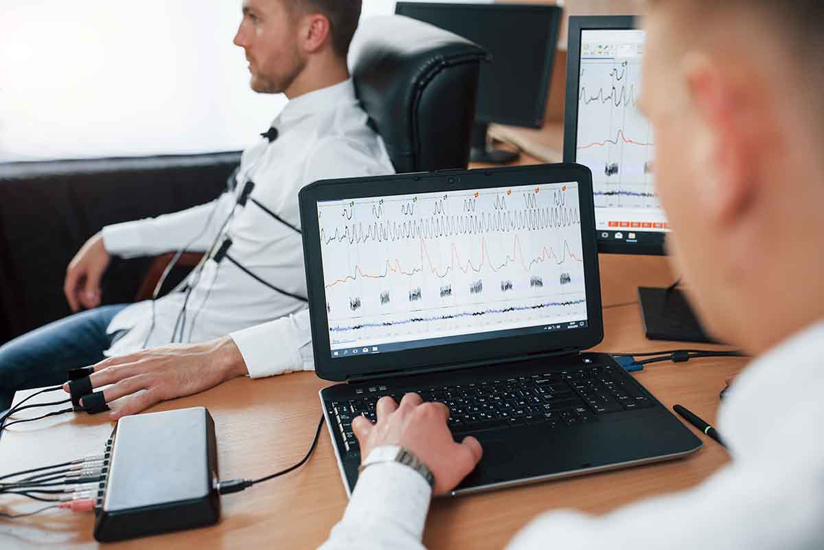 A professional polygraph examination with an examiner in business attire at a desk with a laptop and sensors, carefully observing the subject. The subject is seated in a comfortable chair, calm and cooperative, with sensors attached to their arm and fingers, and a pneumograph band around the chest. 