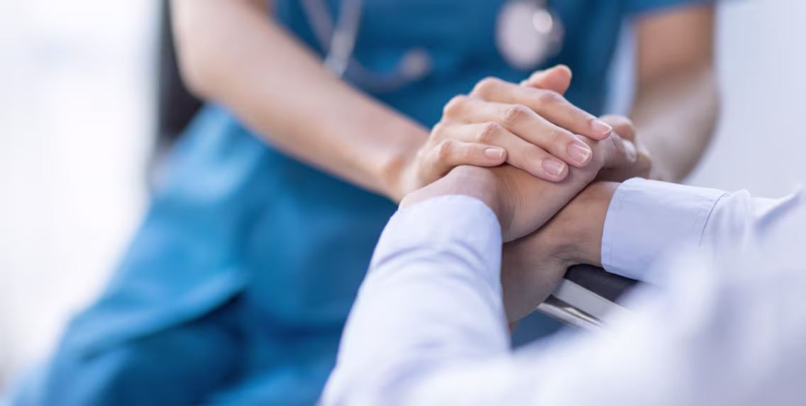 Nurse holding a patient’s hands with care and support