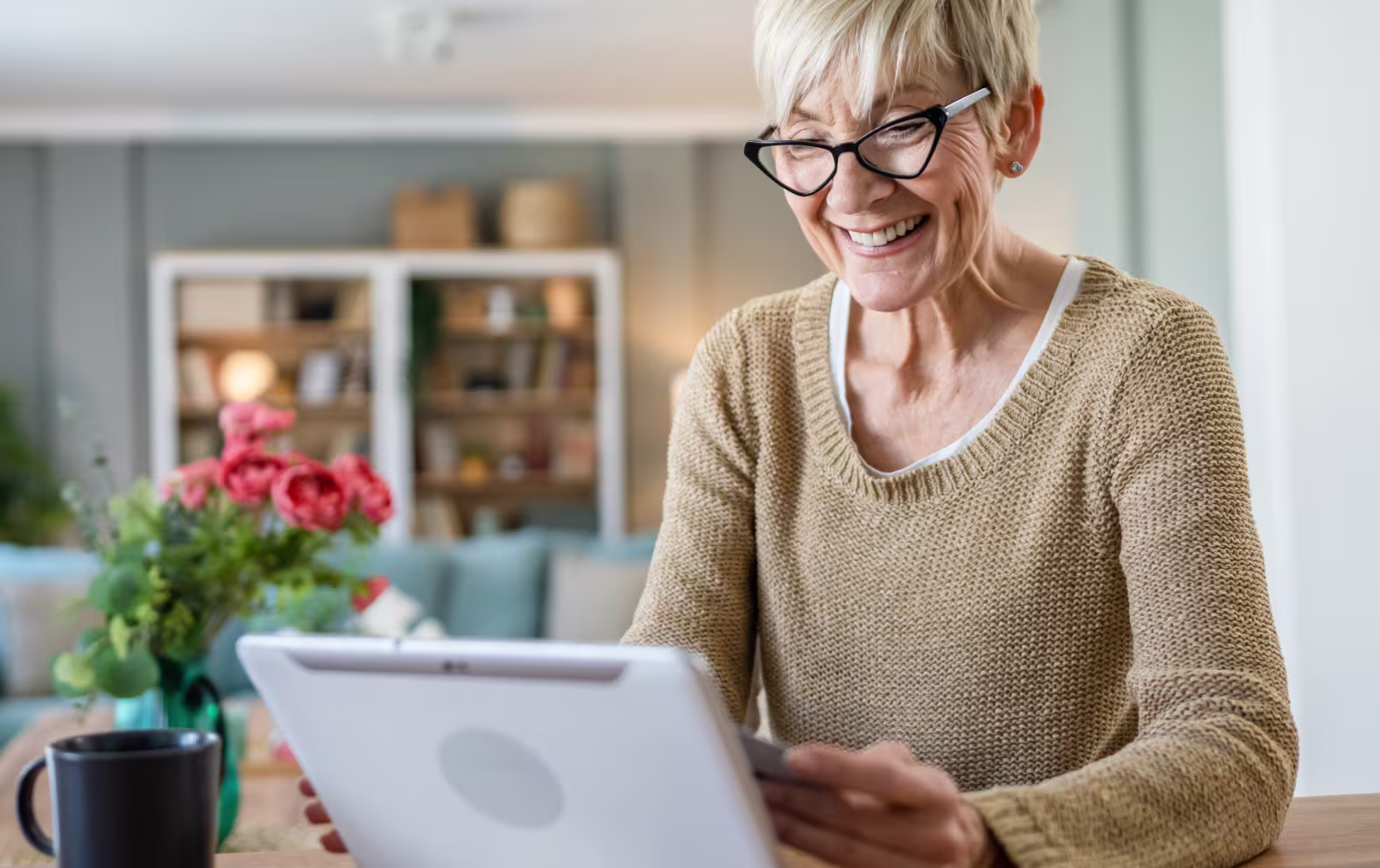 Smiling elderly woman wearing glasses looking at a tablet
