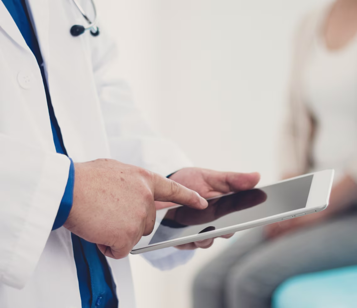 Doctor in a white coat using a tablet during consultation