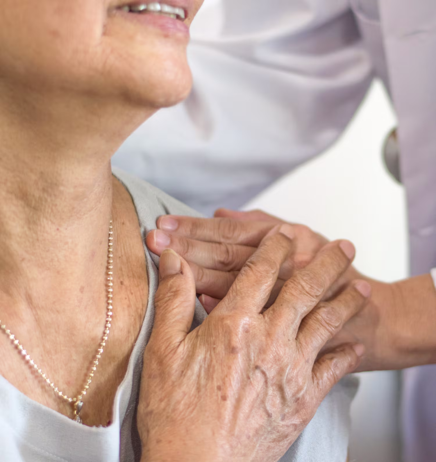Elderly woman receiving gentle shoulder support from a caregiver