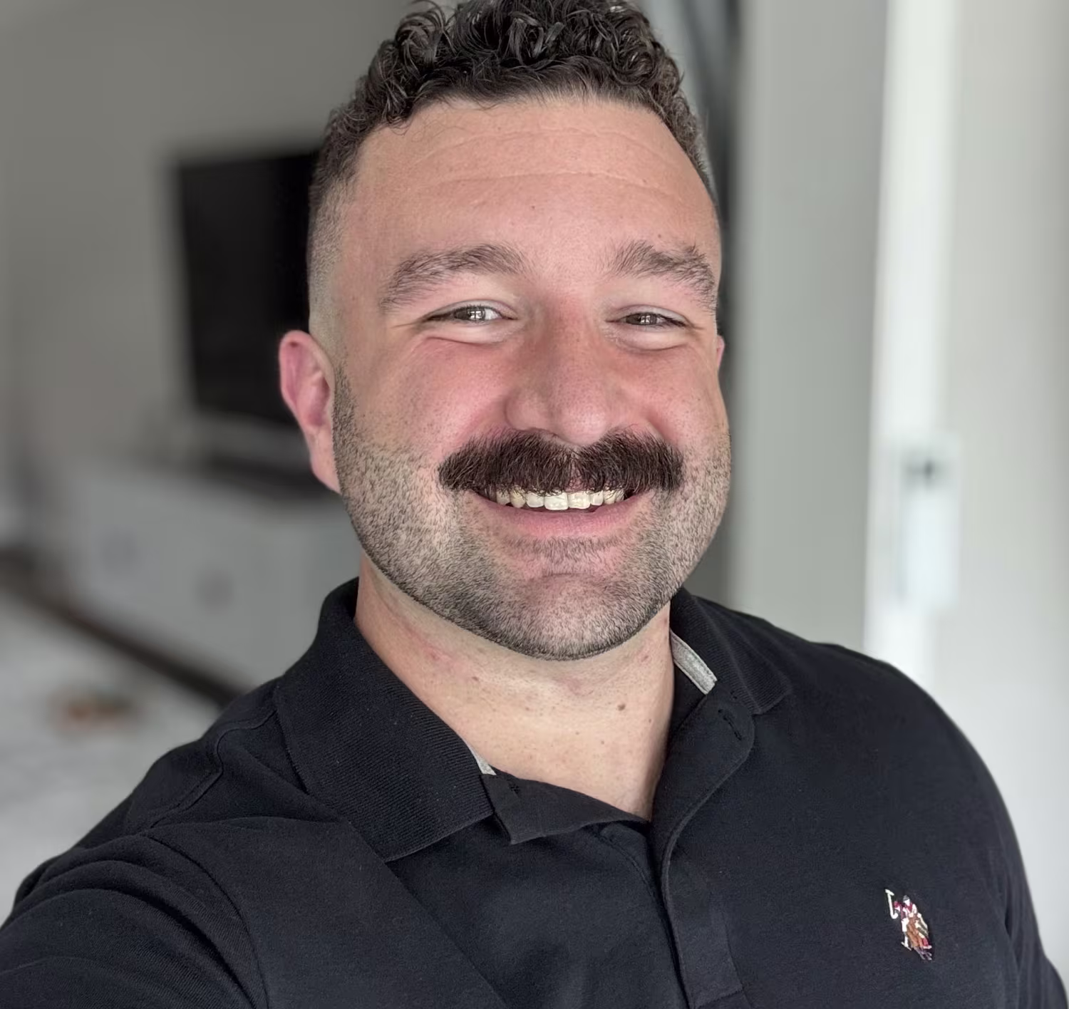 Dr. Zach smiling and wearing a black polo shirt indoors