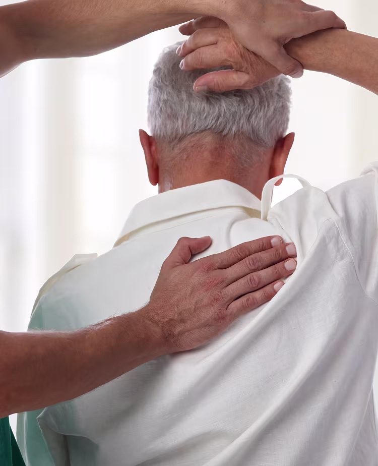 Healthcare professional assisting an elderly man with a shoulder and upper back mobility exercise