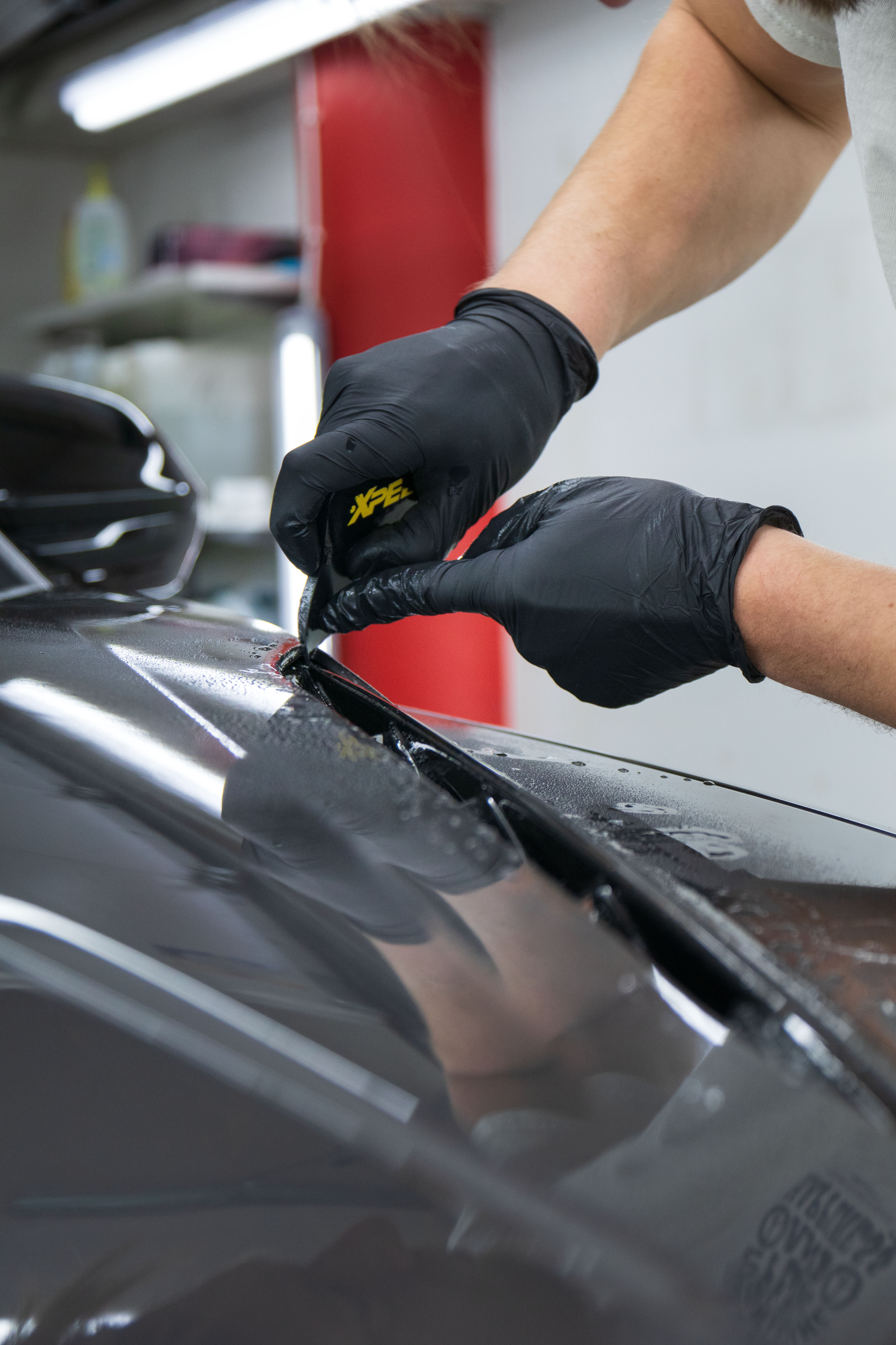 Närbild på AutoShield installatör som arbetar med XPEL stenskottsfilm ppf