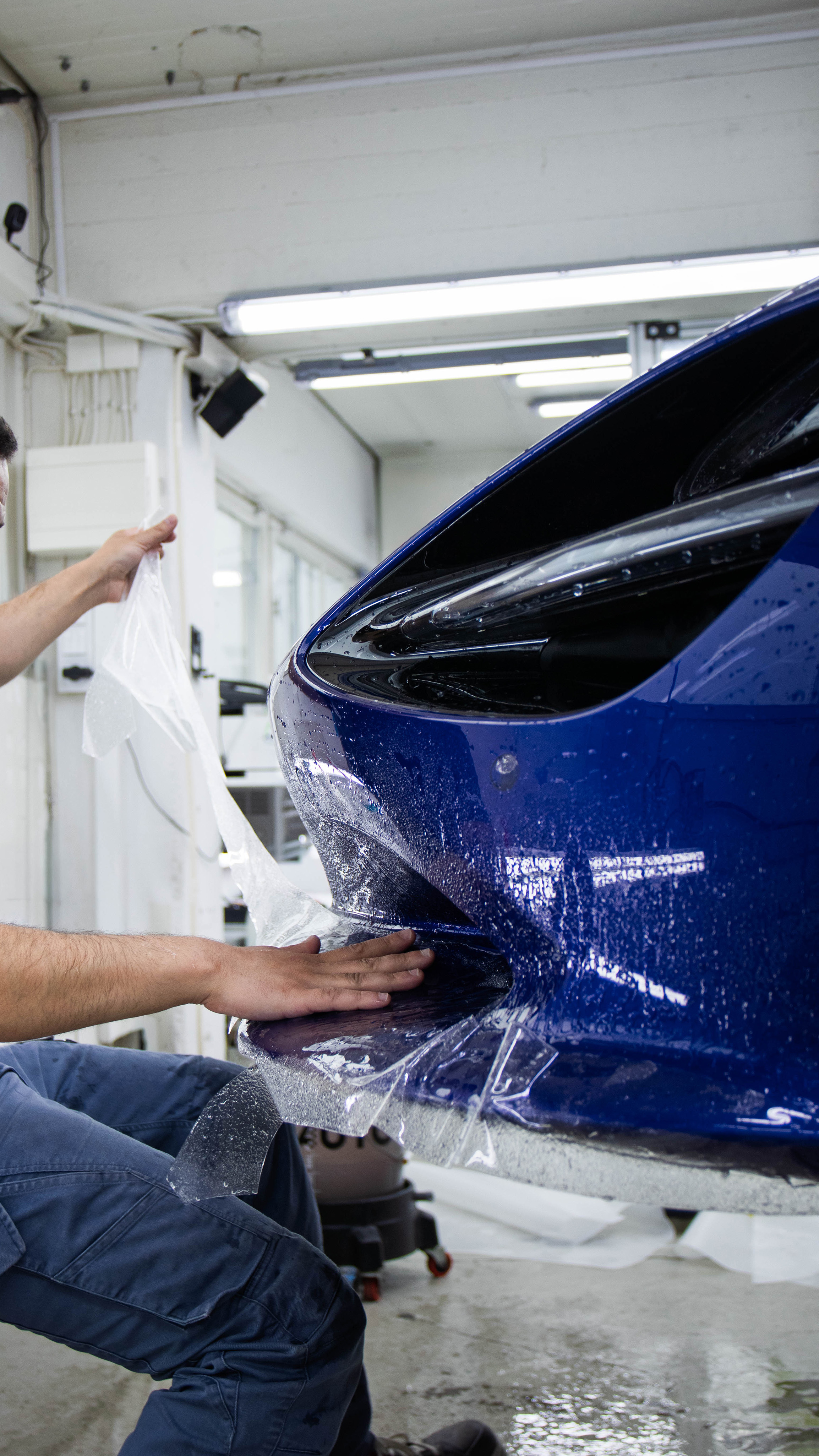Installatör applicerar stenskottsfilm ppf på blå bil hos AutoShield