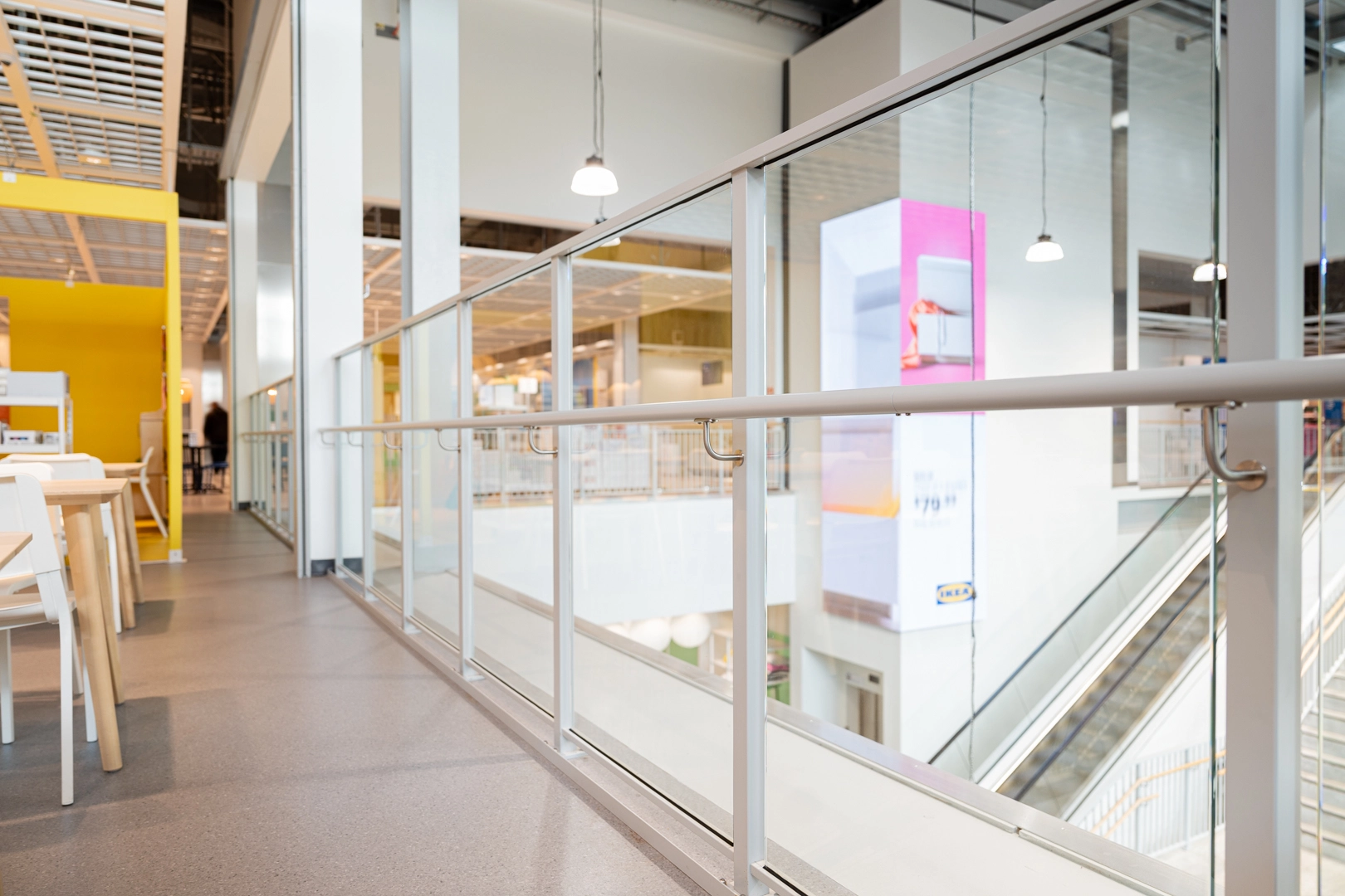 Glass Attache balustrade with handrail installed along an indoor commercial walkway