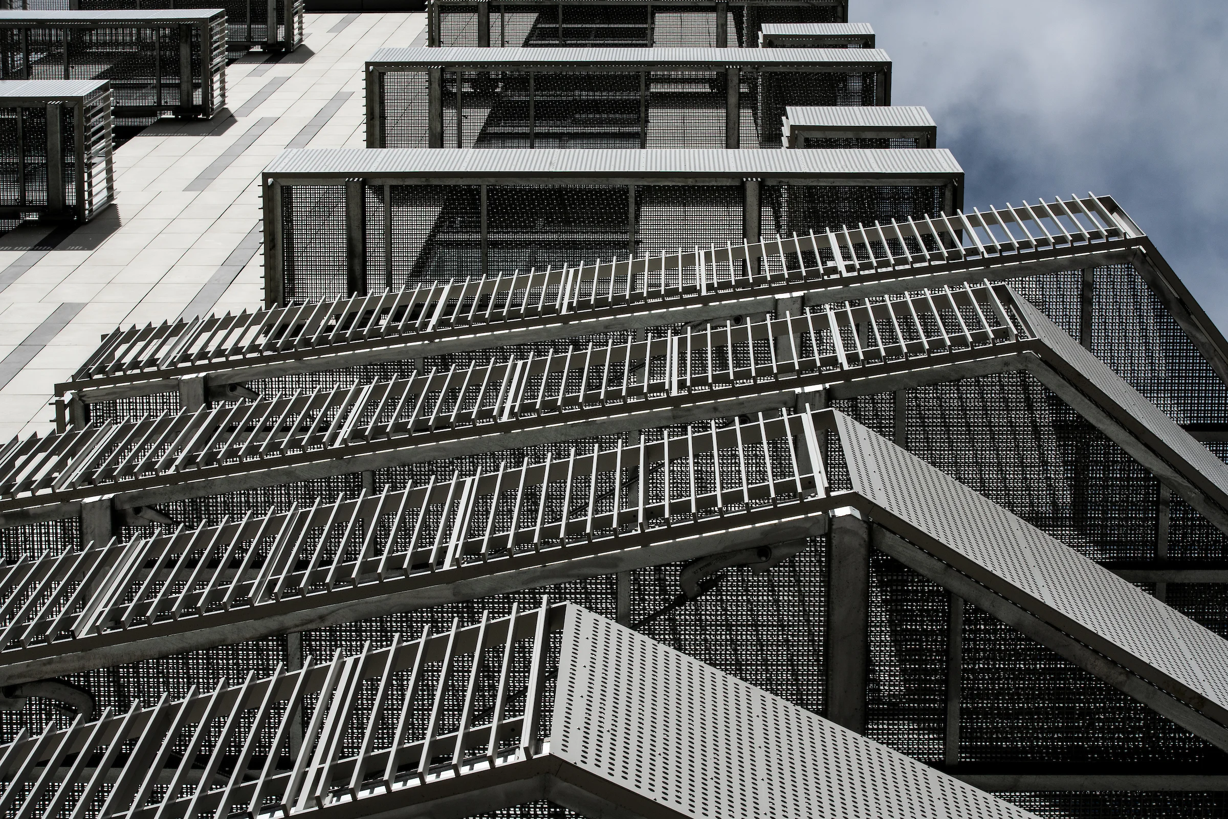Close-up view of the Belcanto façade showing layered Sleeper balconies with metal screens and Attache Balustrade detailing.
