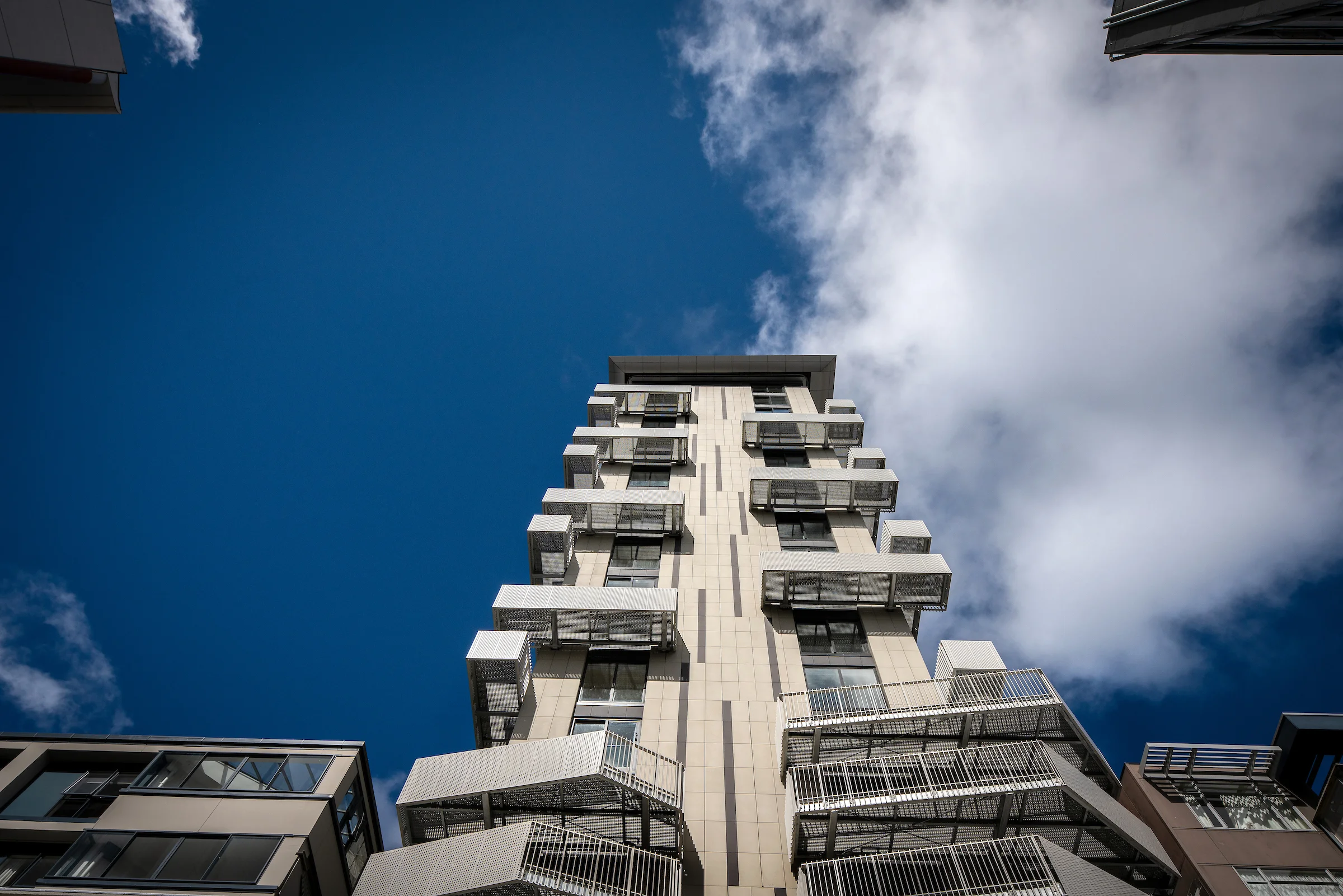 Low-angle view of the Belcanto building at 111 Dixon Street featuring Sleeper balconies and Attache Balustrade detailing against a blue sky.