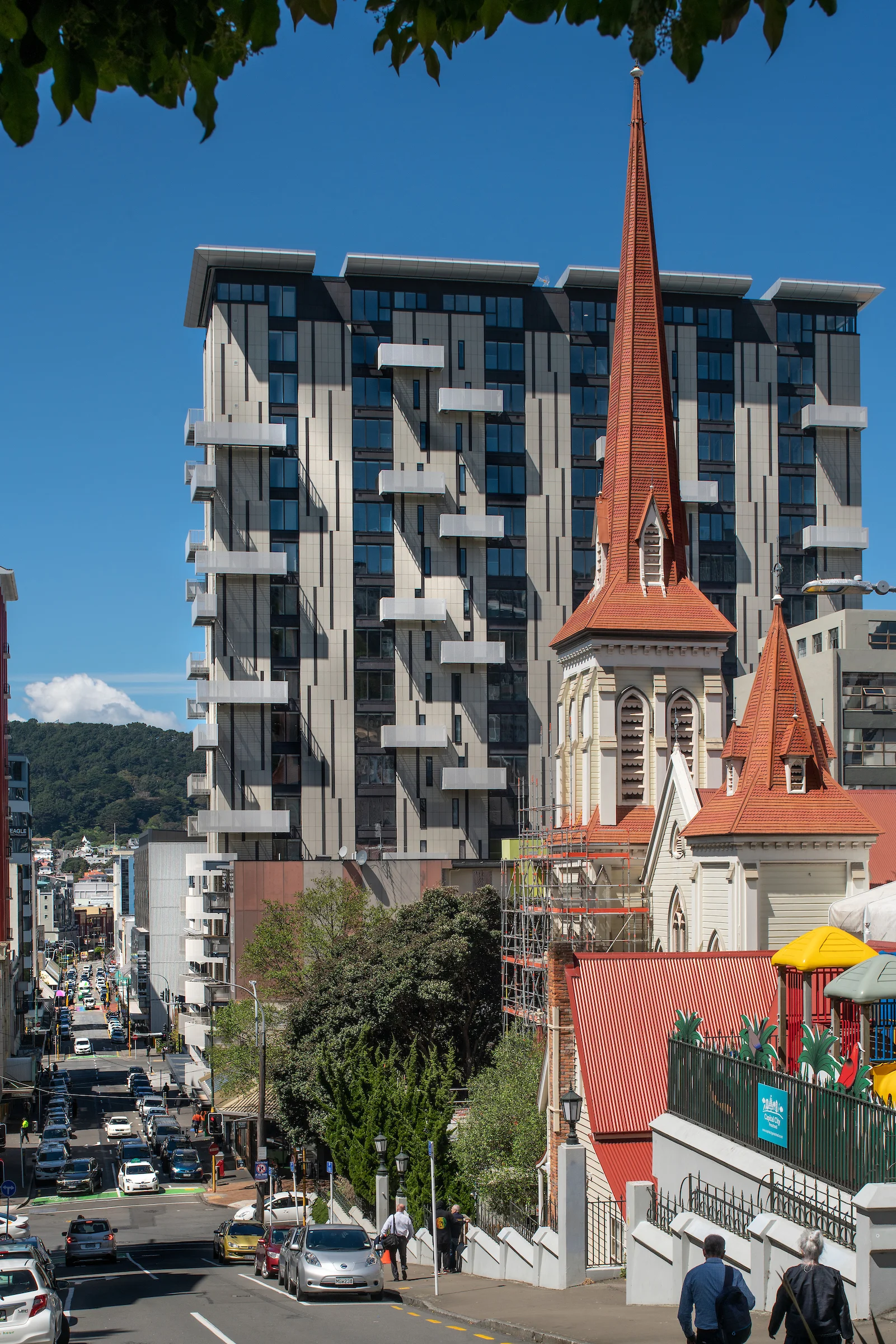 Belcanto building rising behind a historic church, with its modern façade and distinctive Sleeper balconies visible across the tower.