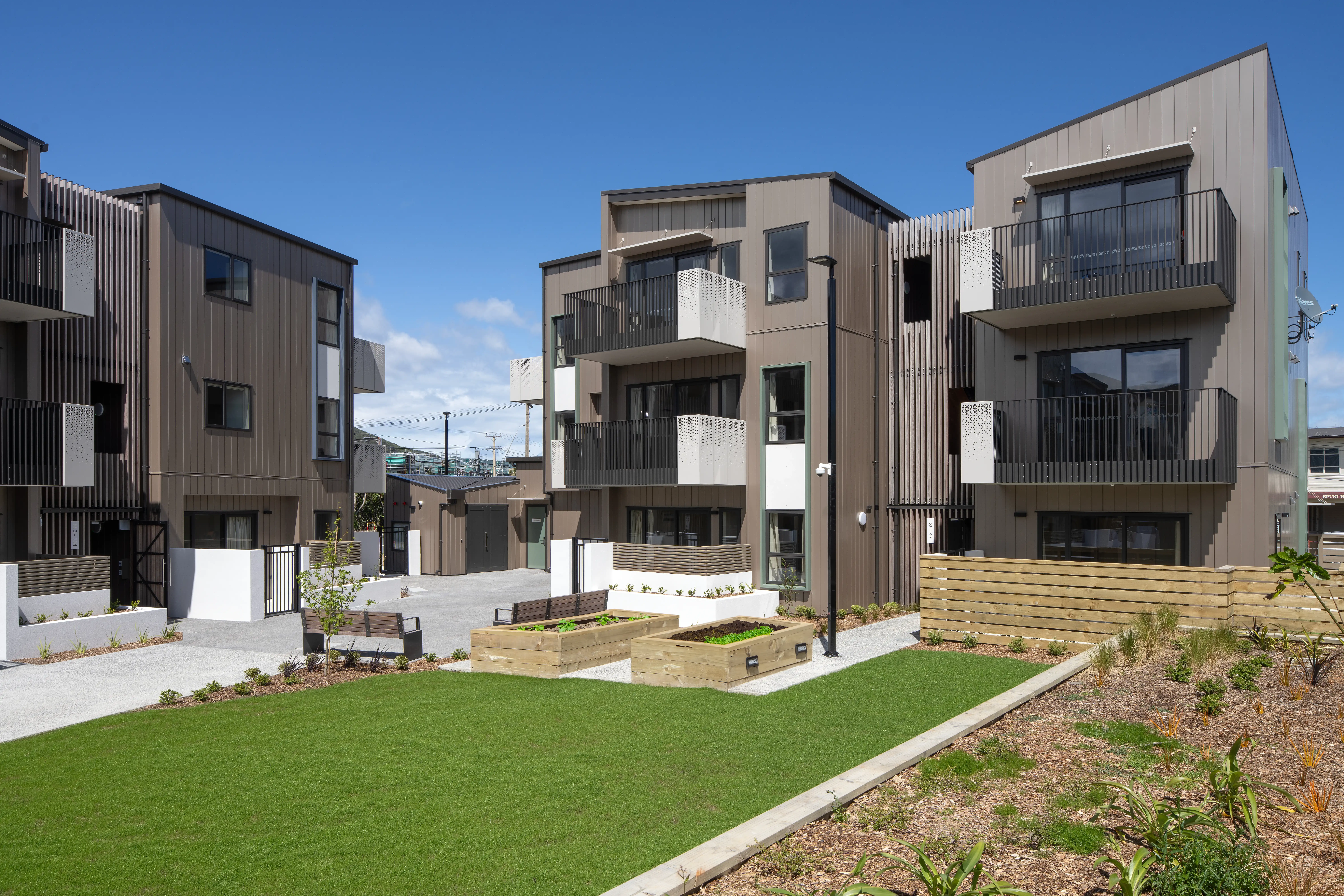 Two apartment buildings set at a slight angle at Oxford Terrace, their balconies overlooking a shared central garden.