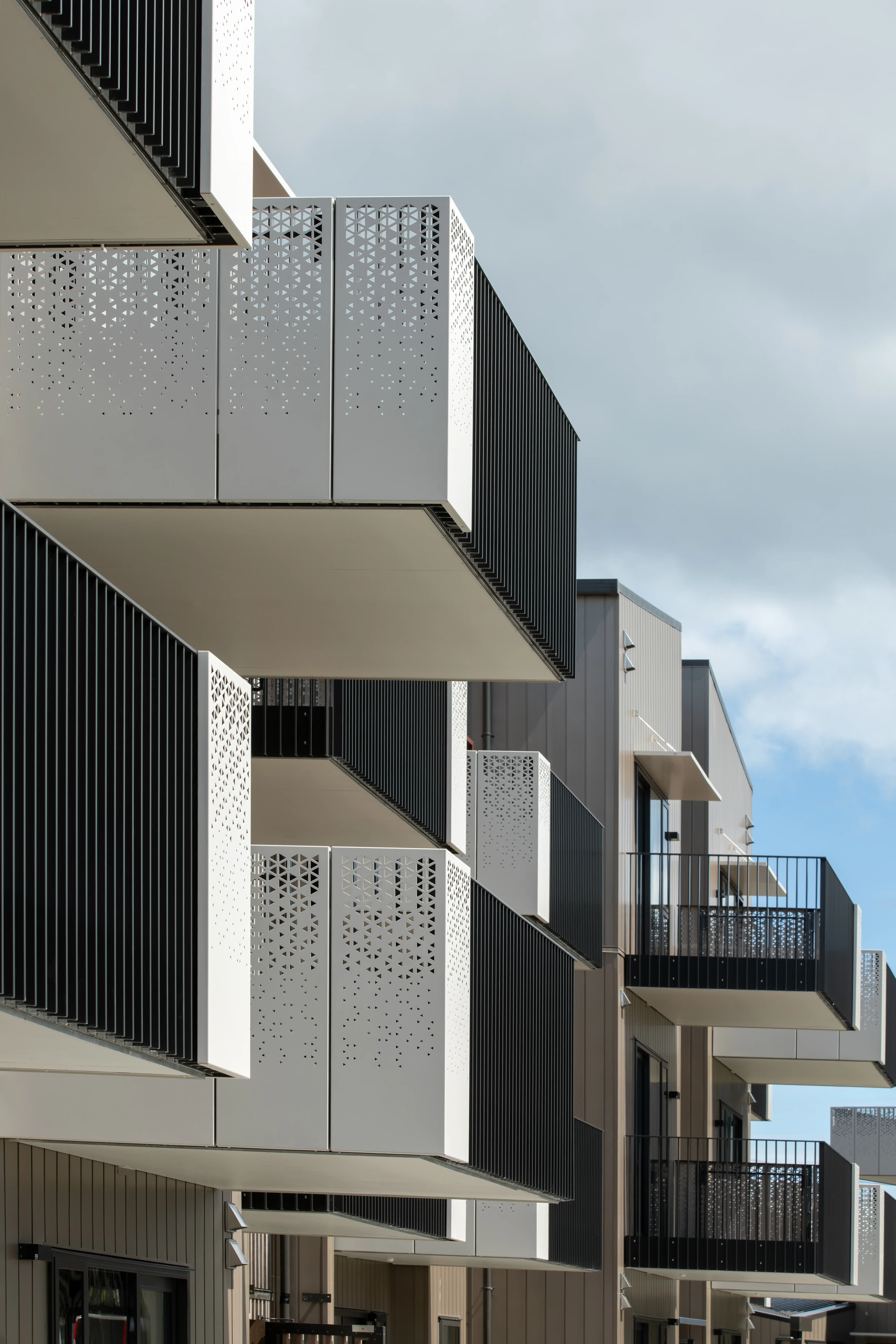 Looking up at stacked glide-on balconies at Oxford Terrace, each fronted with a laser-cut aluminium screen.