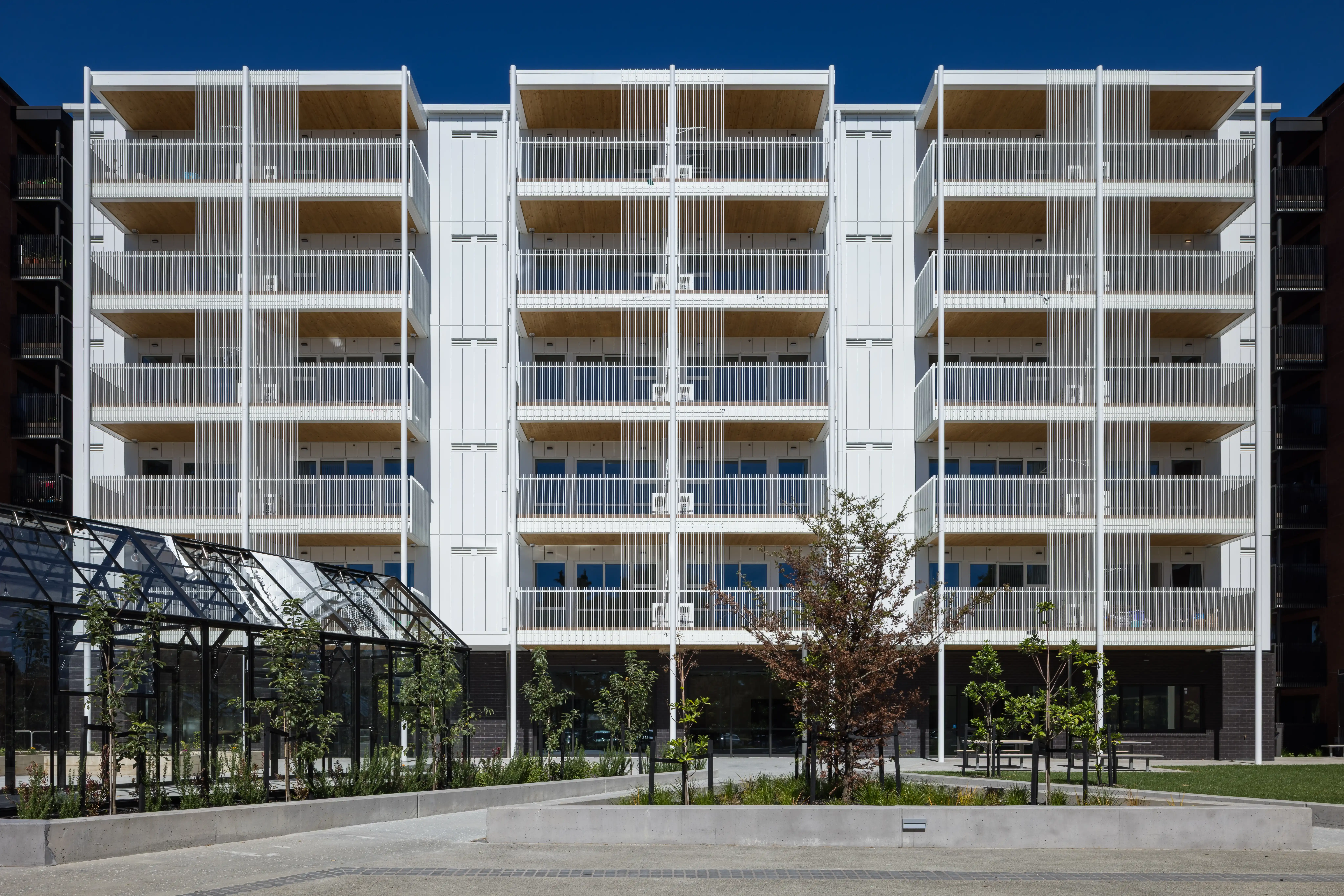 Aluminium balustrades and screens create a consistent architectural rhythm across Community Lane's five buildings.
