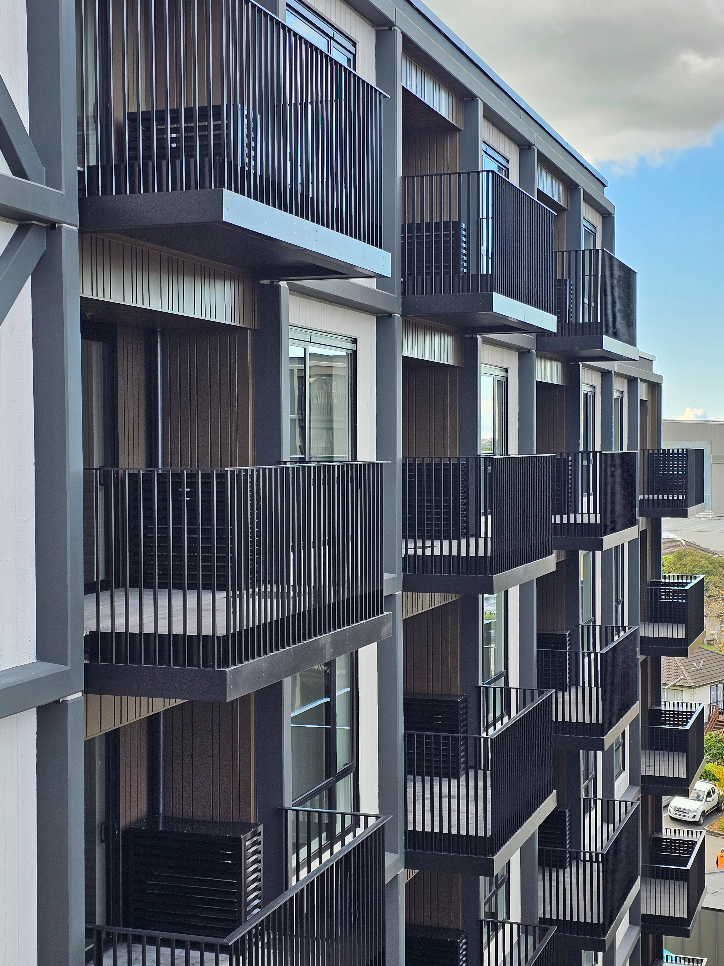 Resido Sylvia Park's three apartment towers in Auckland, lined with build-to-rent balustrades in vertical aluminium fins.