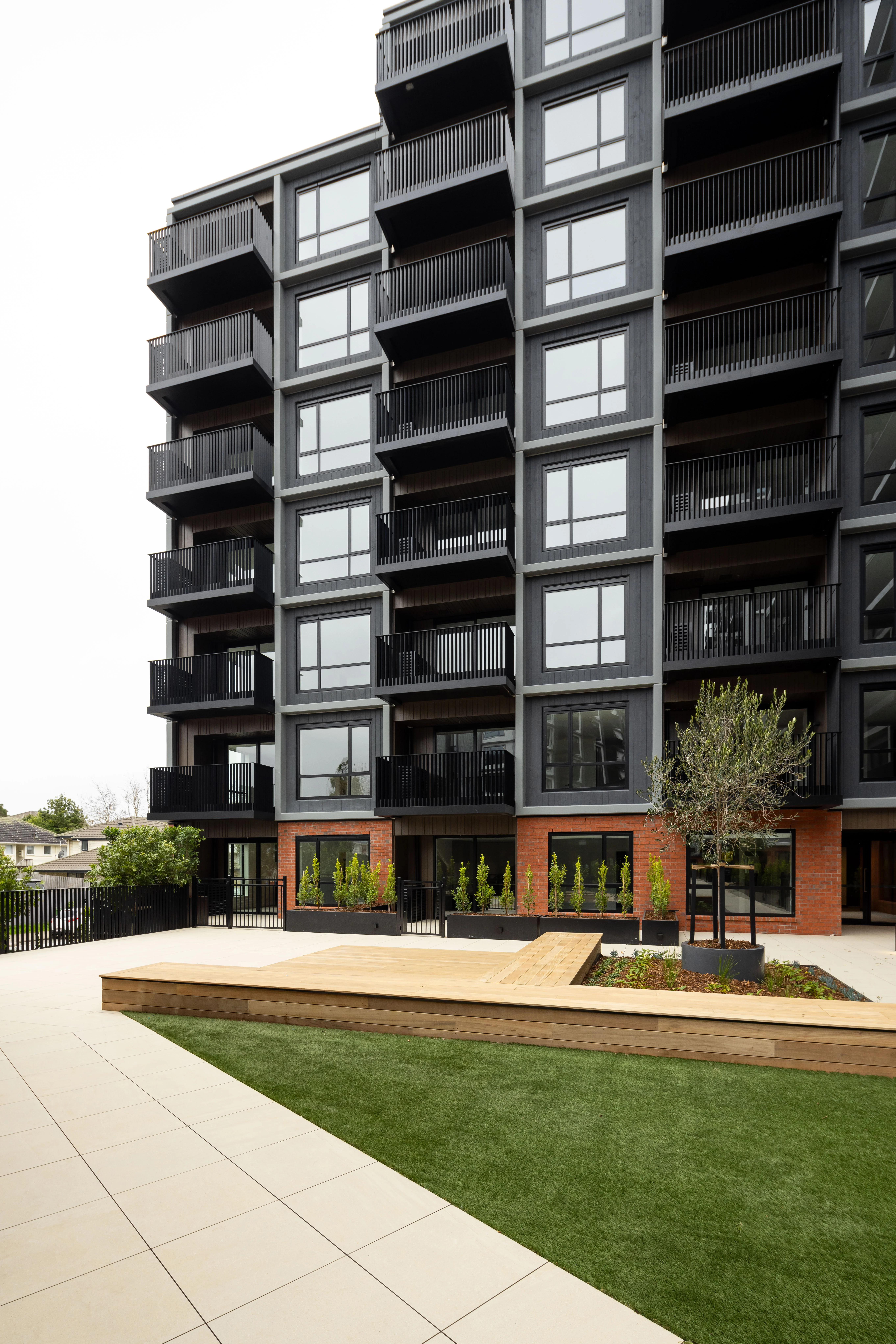 Resido build-to-rent apartments at dusk, lit windows glowing behind rows of vertical aluminium fins.
